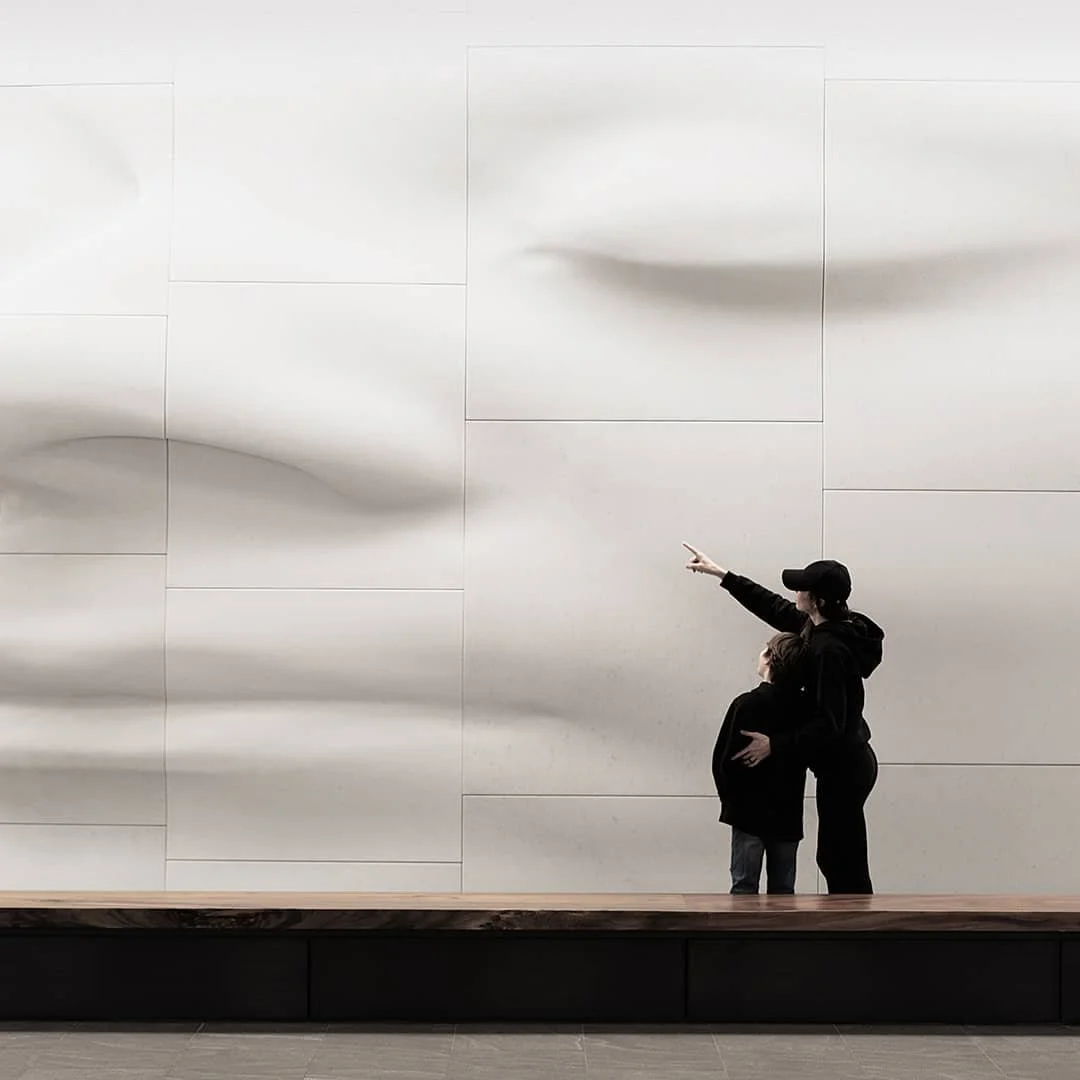 adult and child standing before large sculptural wall installation commercial location photography
