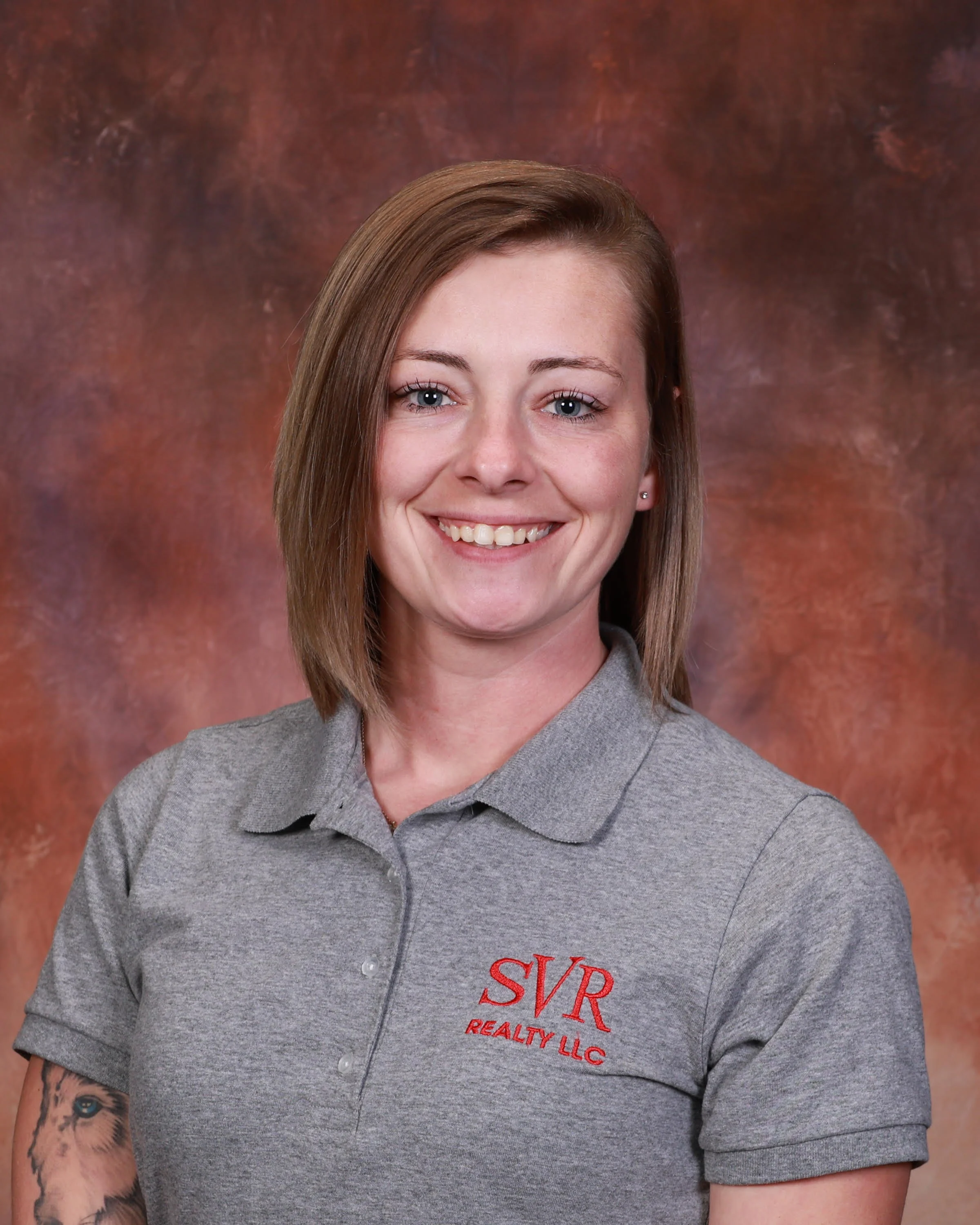 A woman with long blonde hair smiling at the camera in a nighttime setting with neon lights in the background.