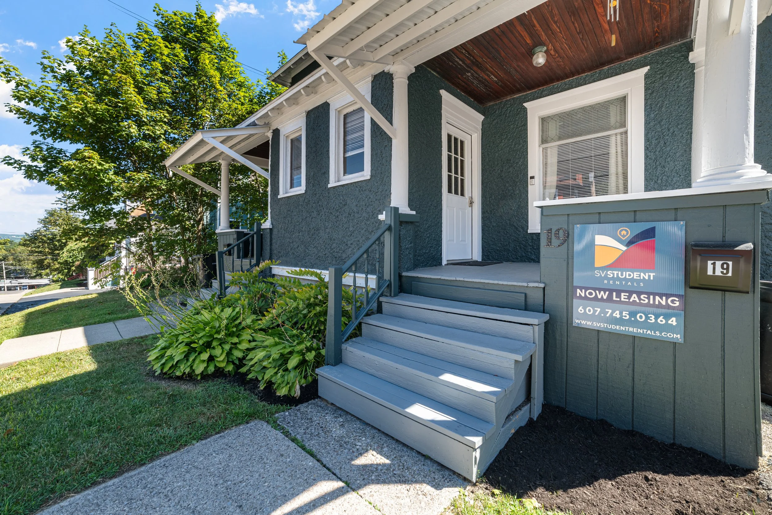 Exterior of a house with a porch, stairs, and a sign indicating it is now leasing through SV Student Rentals.