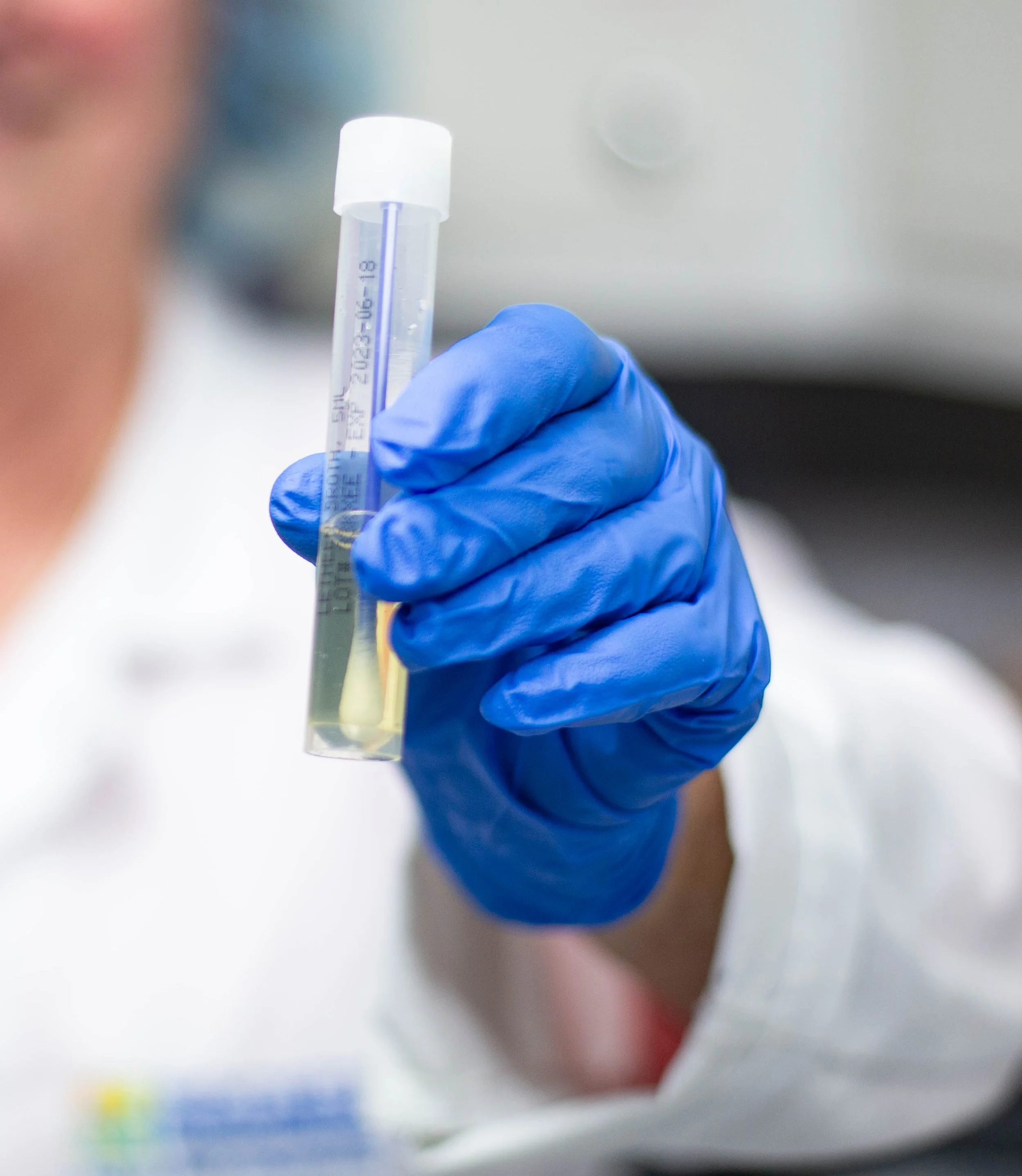 Rocket Products lab worker wearing blue gloves holding a test tube with a lemonade concentrate inside.