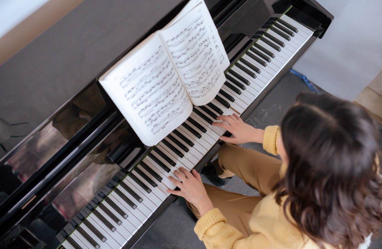 Child playing piano with sheet music open on the stand.