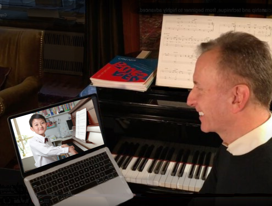 A man is smiling while looking at a laptop that shows a young girl playing the piano, with sheet music and books on a piano in the background.