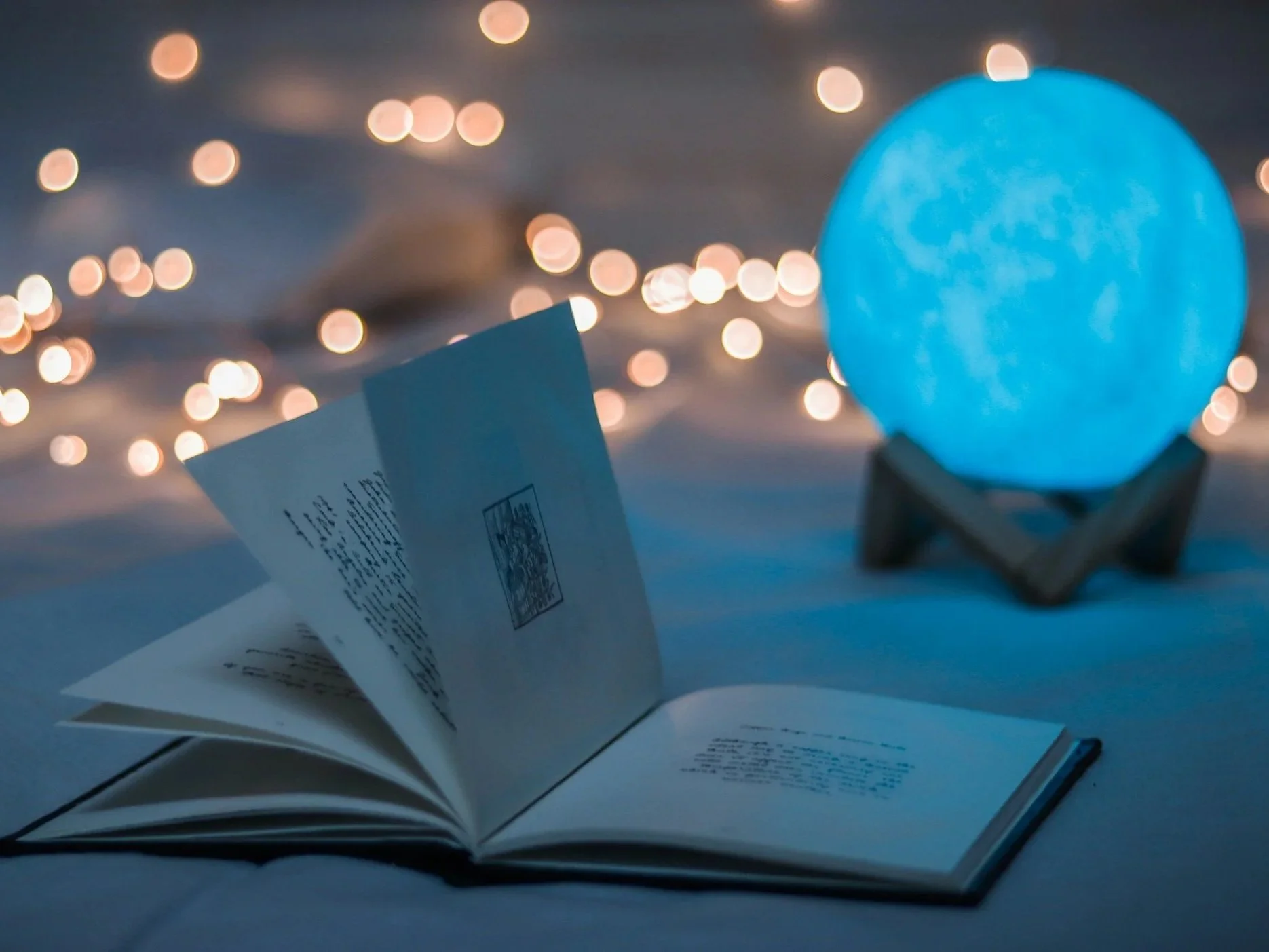 Mystical book with fairy lighting and a moon lamp in the background