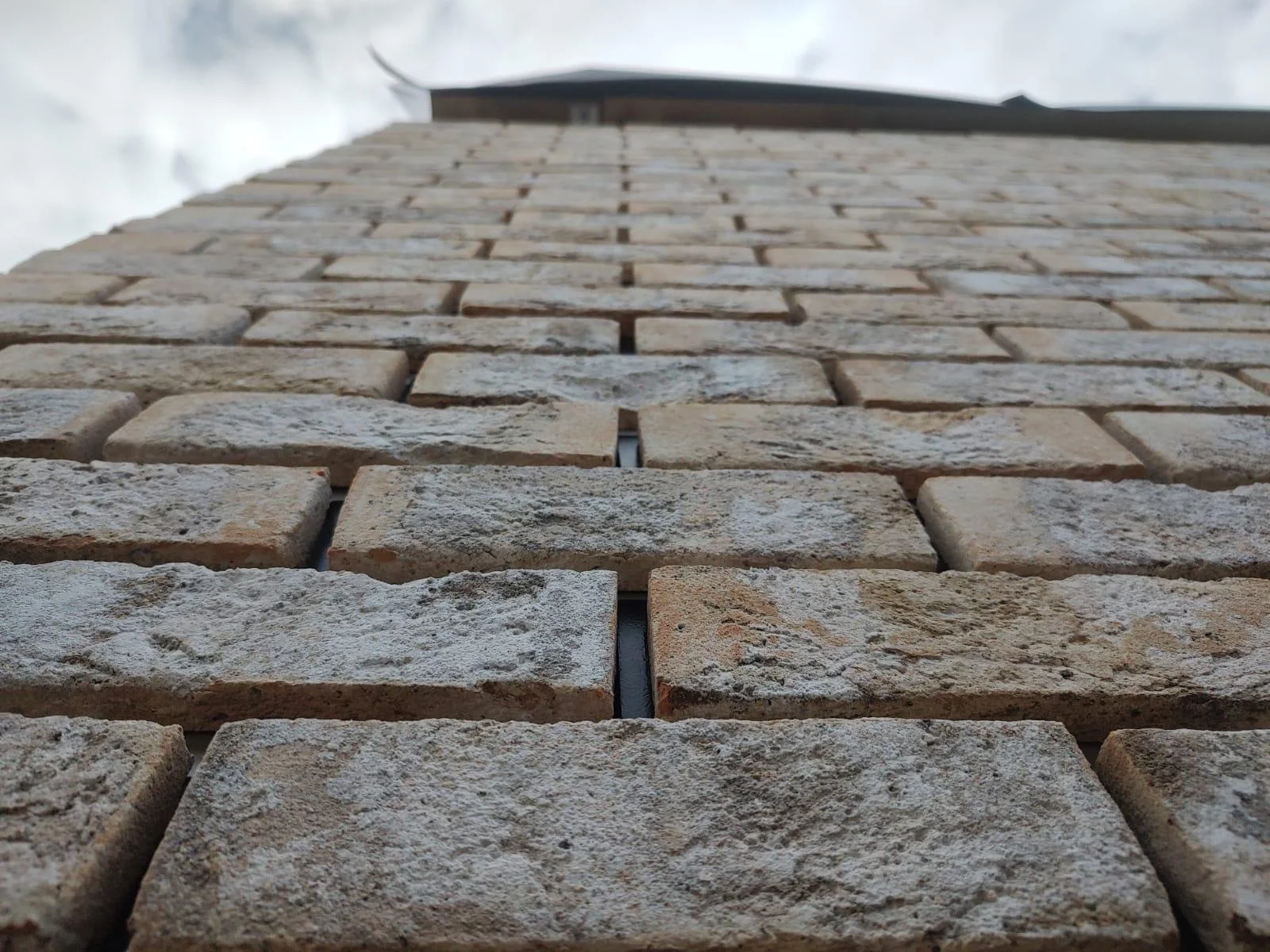 Close-up view of a brick wall taken from the bottom looking up to the sky.