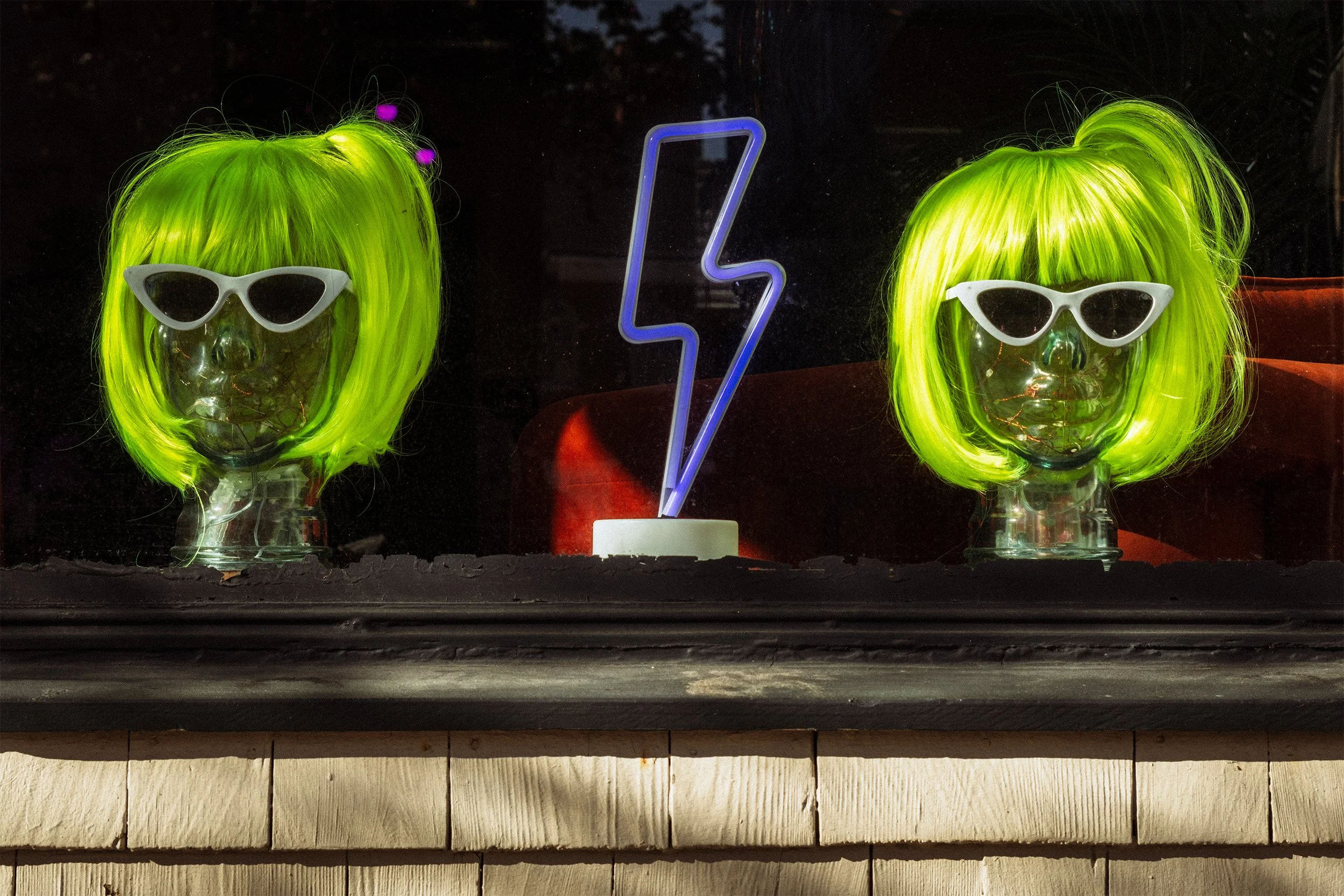 Two clear wig model heads with neon green wigs.