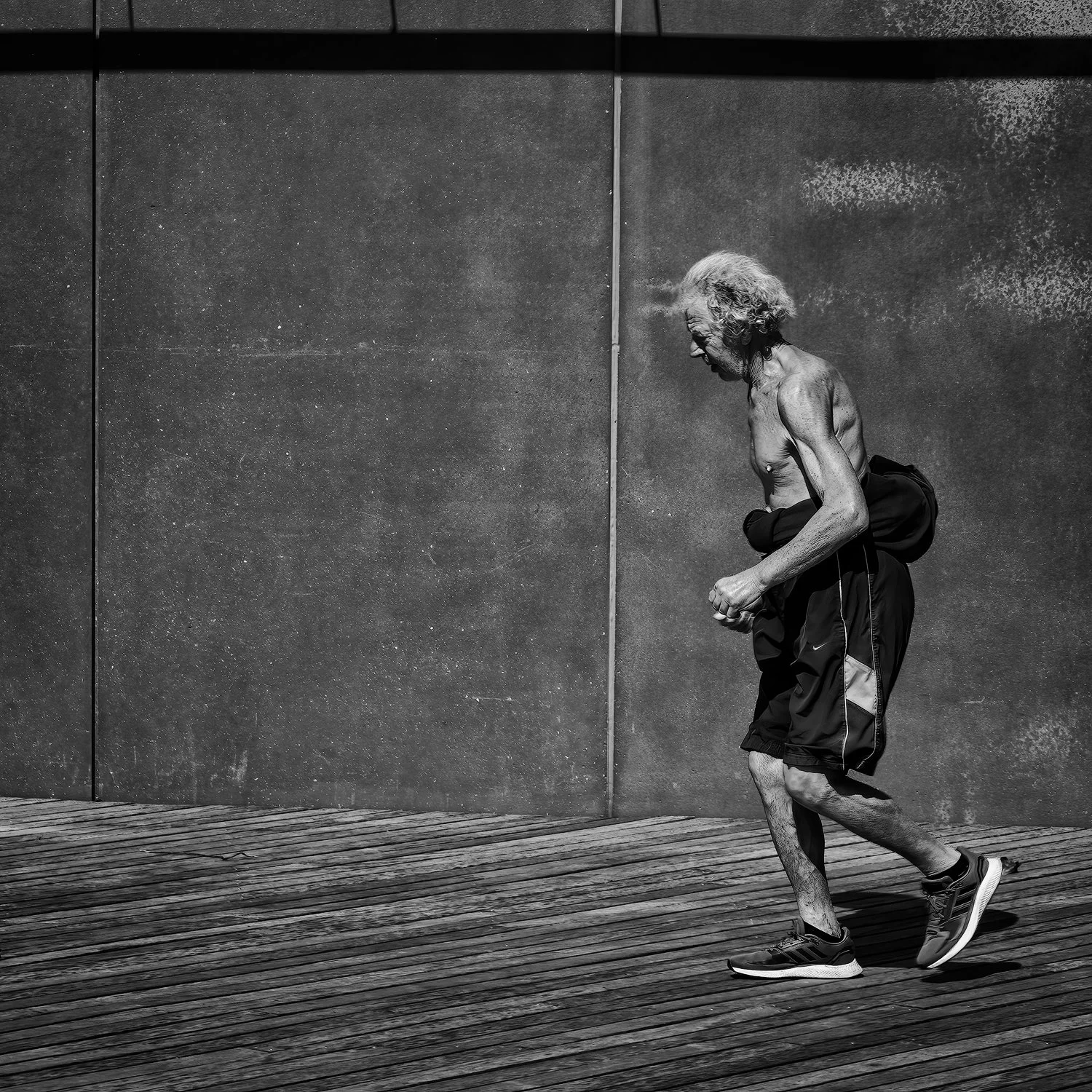 A older man running on the boardwalk along Brighton Beach, NYC.