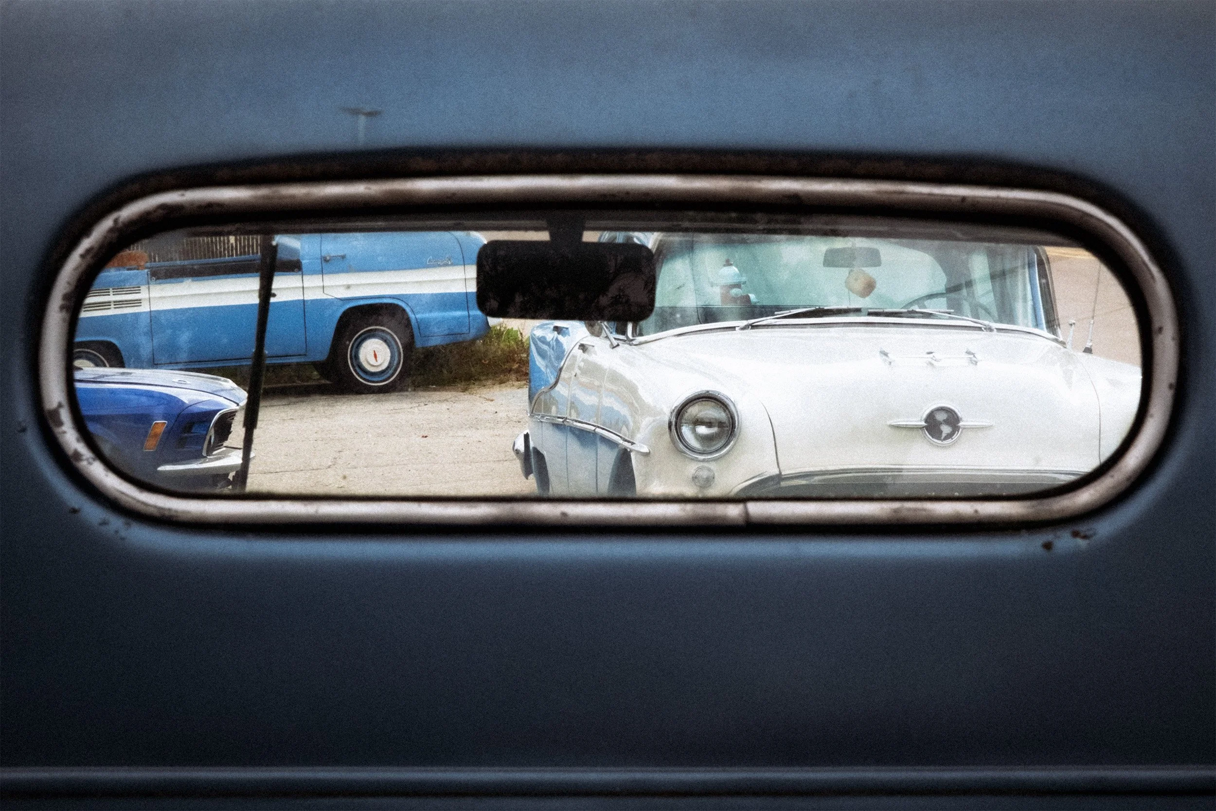Image of cars and a van taken through the rear window of a 1960's Ford pick-up truck. 