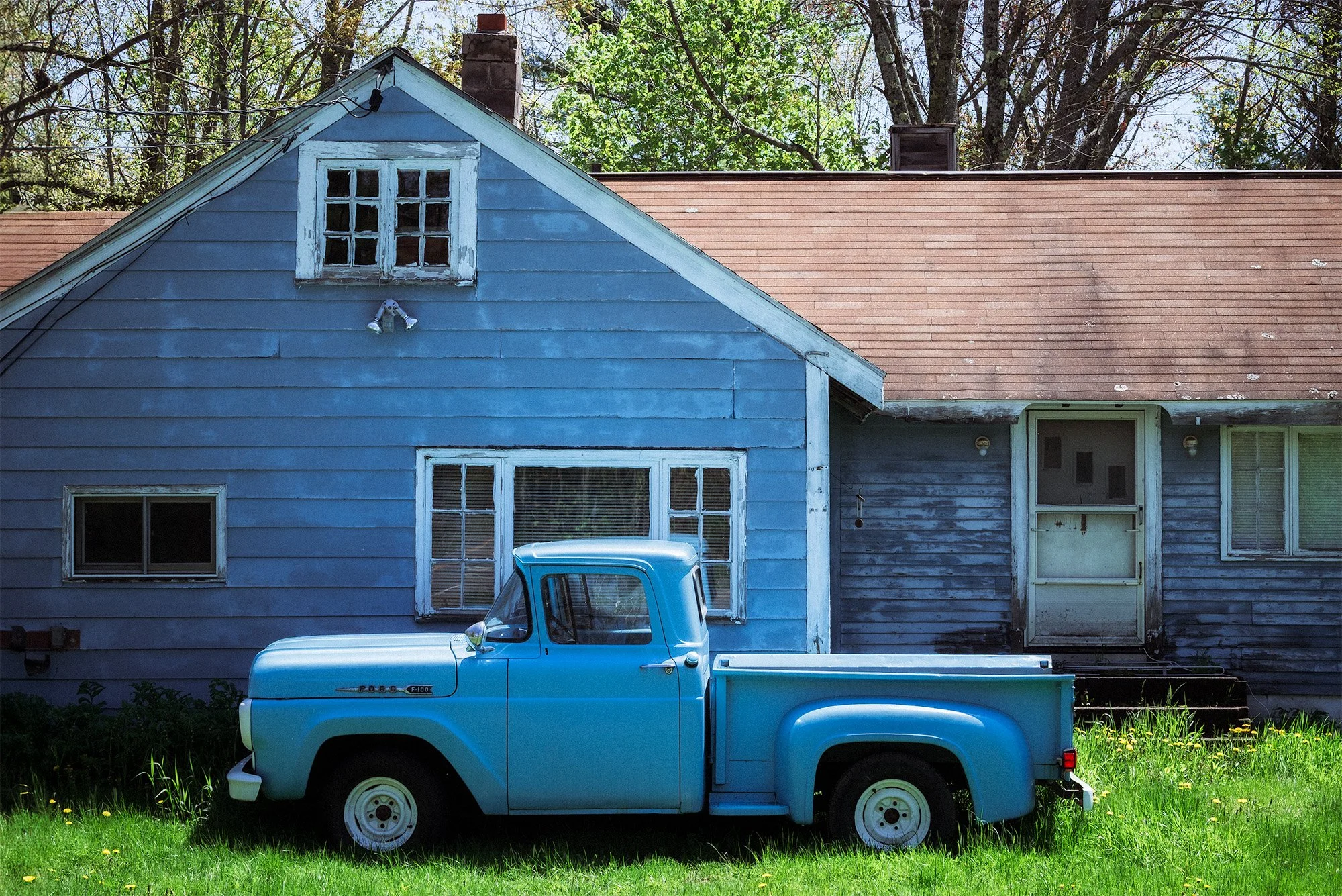 Image of a 1958 blue Ford F-series pick-up truck in front of a blue house.