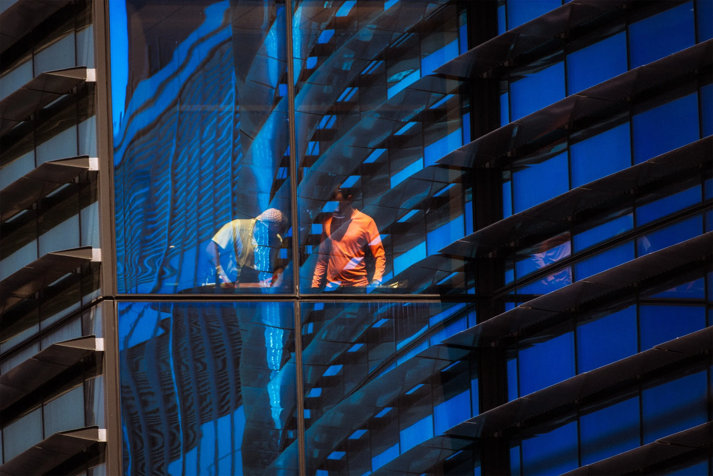 Workers inside a building with blue-tinted windows.