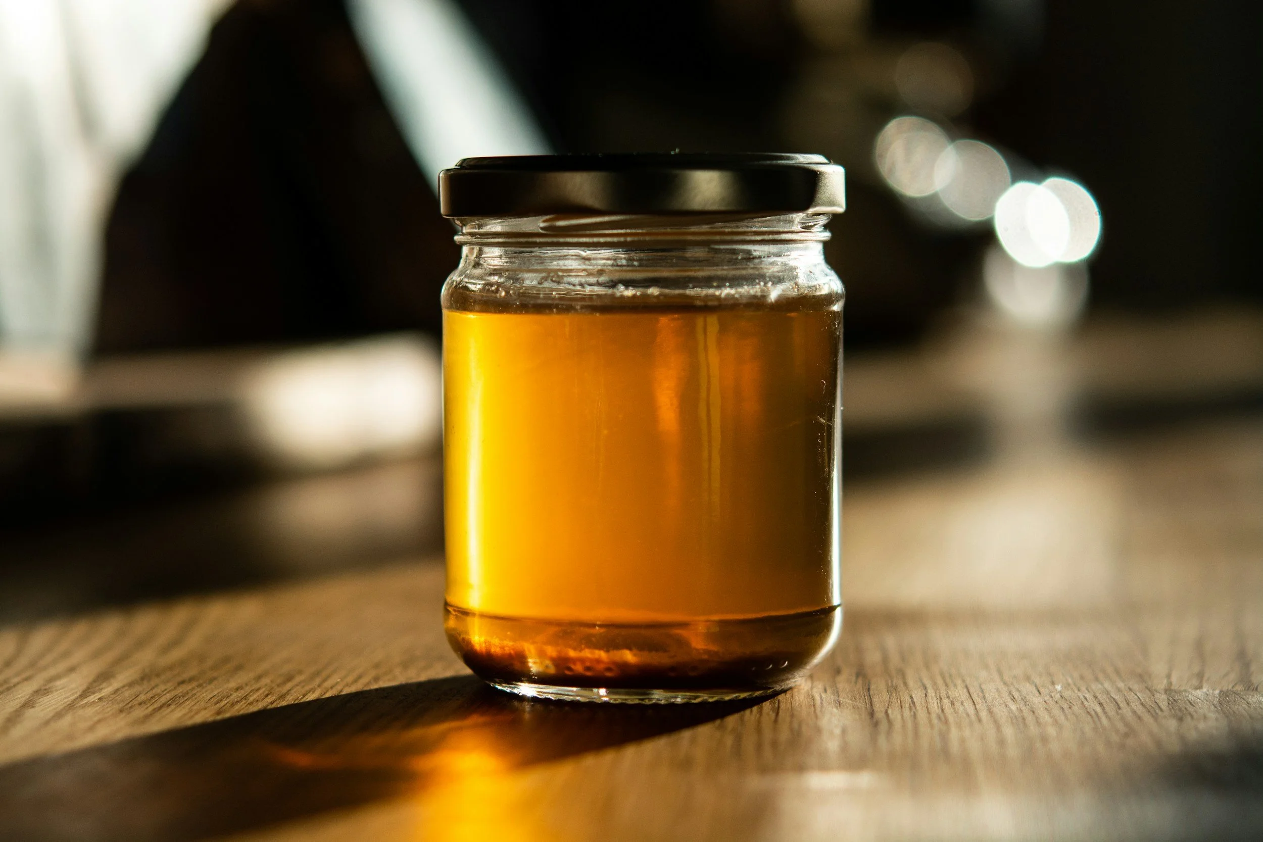 A small glass jar of homemade bone broth with a black lid
