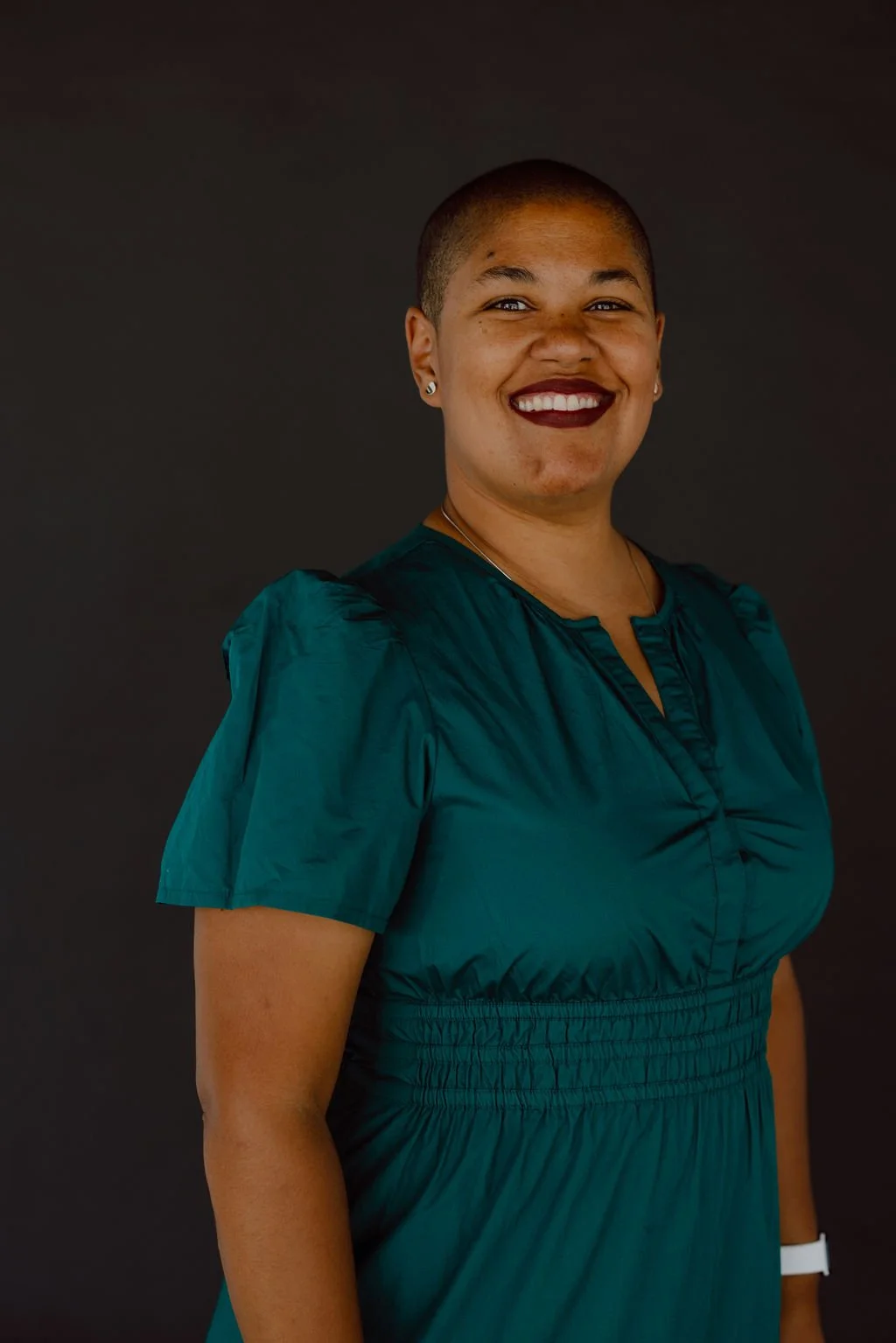 Doula Kelli Blinn in a green dress smiling directly at the camera