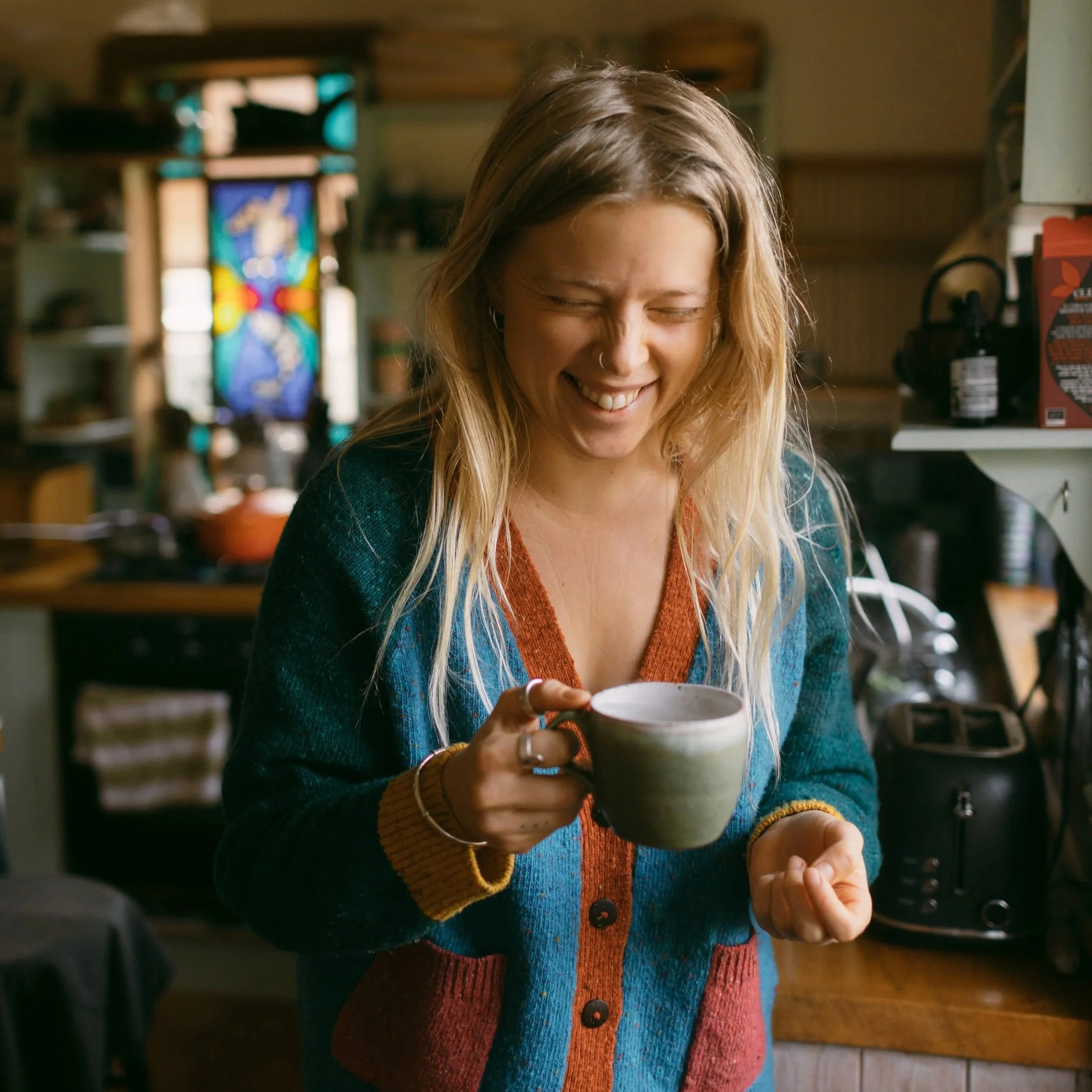 Christabel Courtauld, registered nutritional therapist & health coach, specialising in female hormonal health. DUTCH test interpretation. Laughing with a mug of tea in a kitchen.