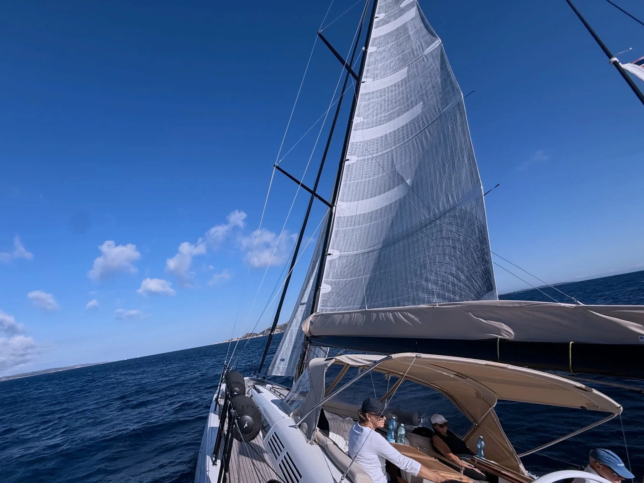 miss marie with large gray sails cruising on the ocean under a blue sky, with passengers aboard.