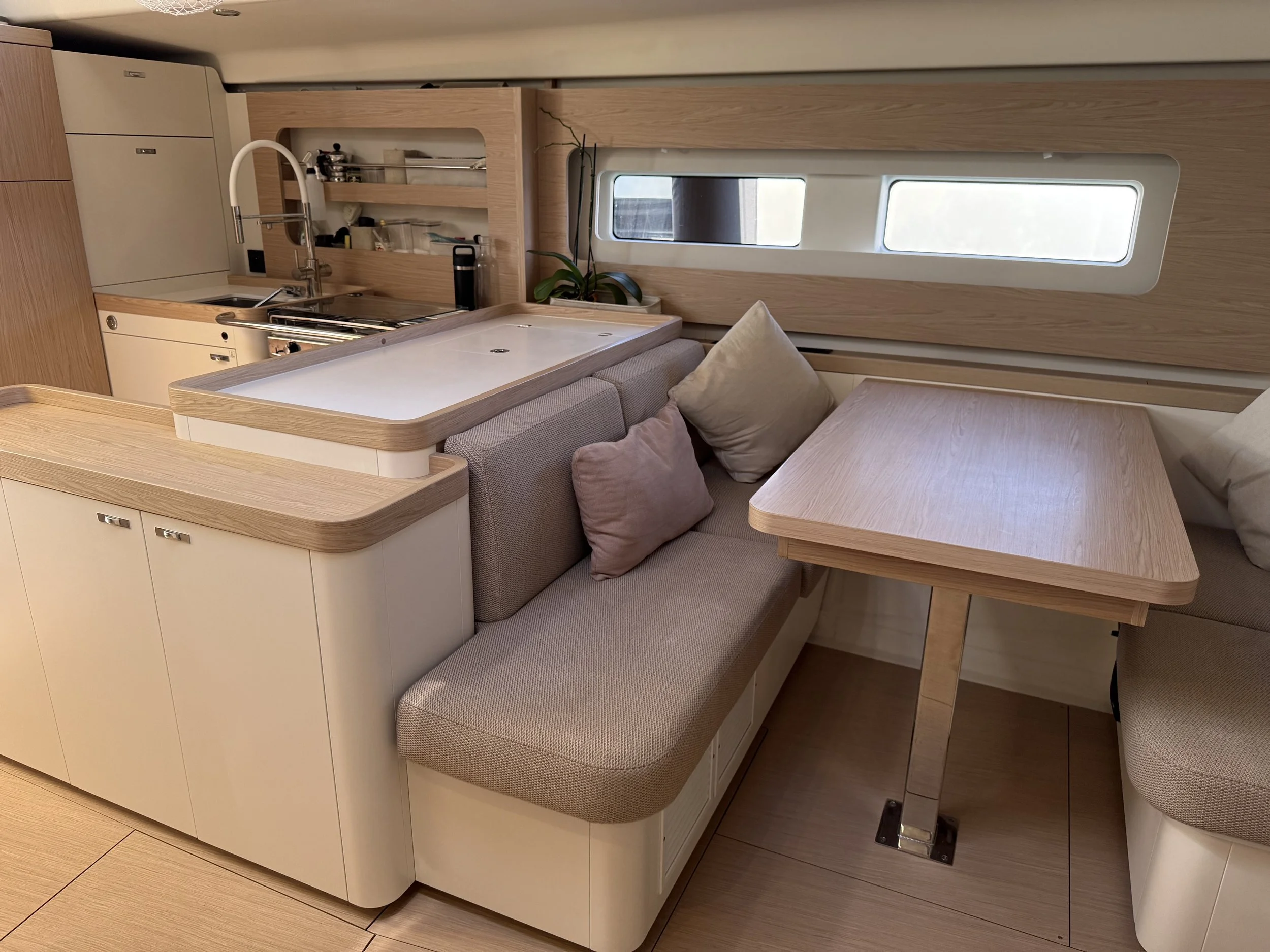 Miss Marie First 53 cabin interior with compact galley, wood cabinetry, cushioned seating, dining table, and large windows
