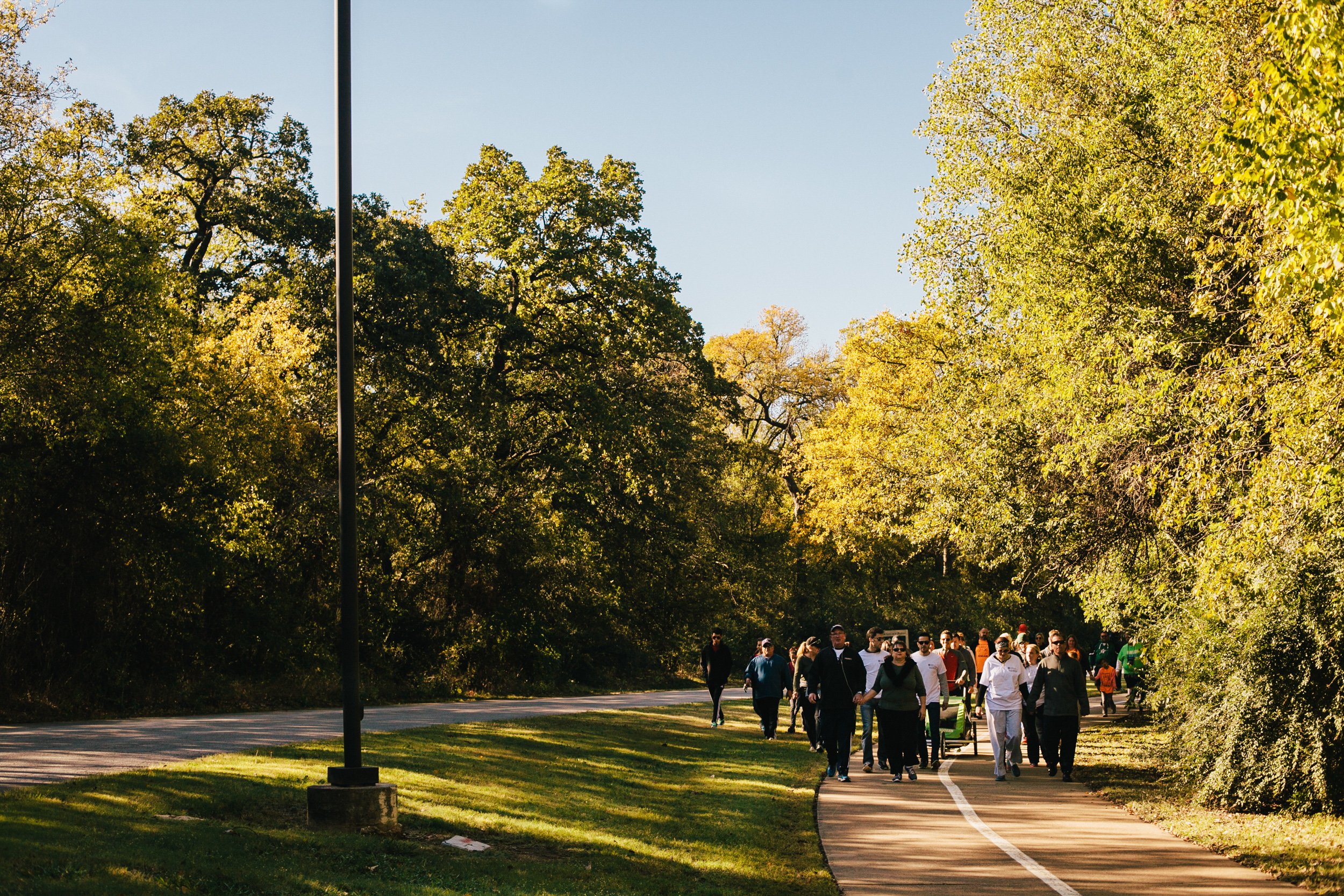 Fundraising walk participants follow a wooded park trail during an outdoor National Psoriasis Foundation charity event in DFW.