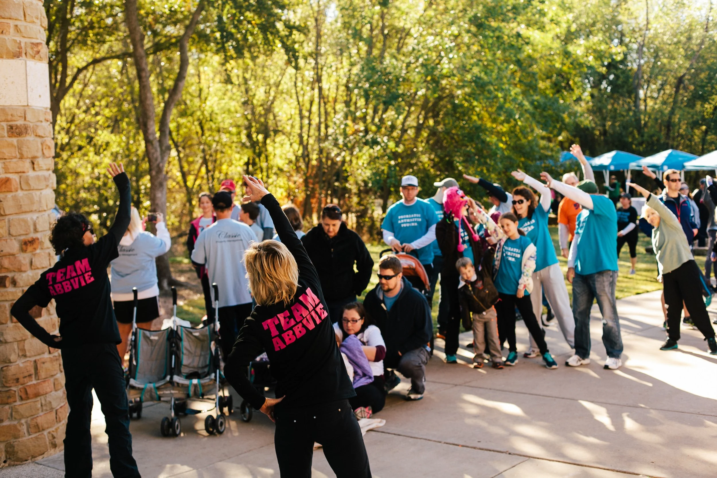 Participants of different ages take part in a group warm-up before a nonprofit charity walk in the Dallas-Fort Worth area.