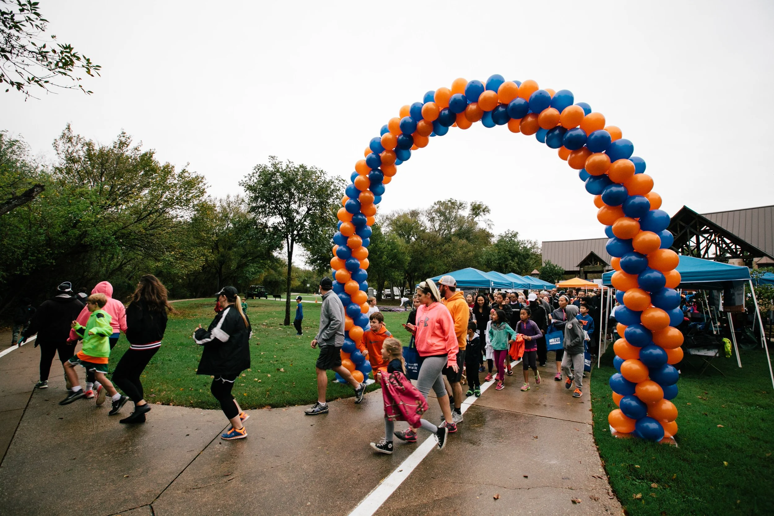 Charity walk participants move through a colorful event arch during a National Psoriasis Foundation fundraising walk in North Texas.
