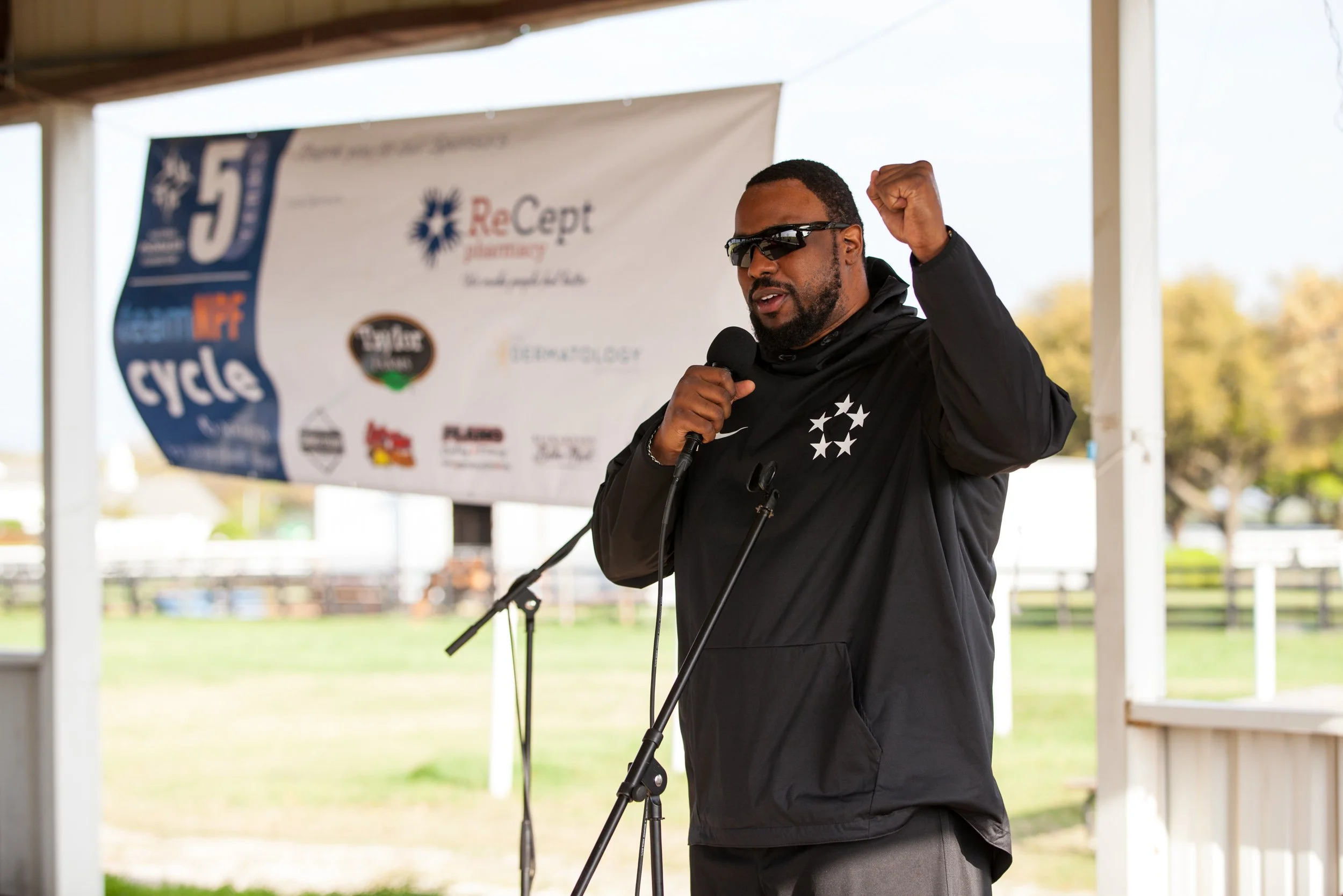 A speaker addresses participants beside sponsor and event branding during a National Psoriasis Foundation fundraising event.