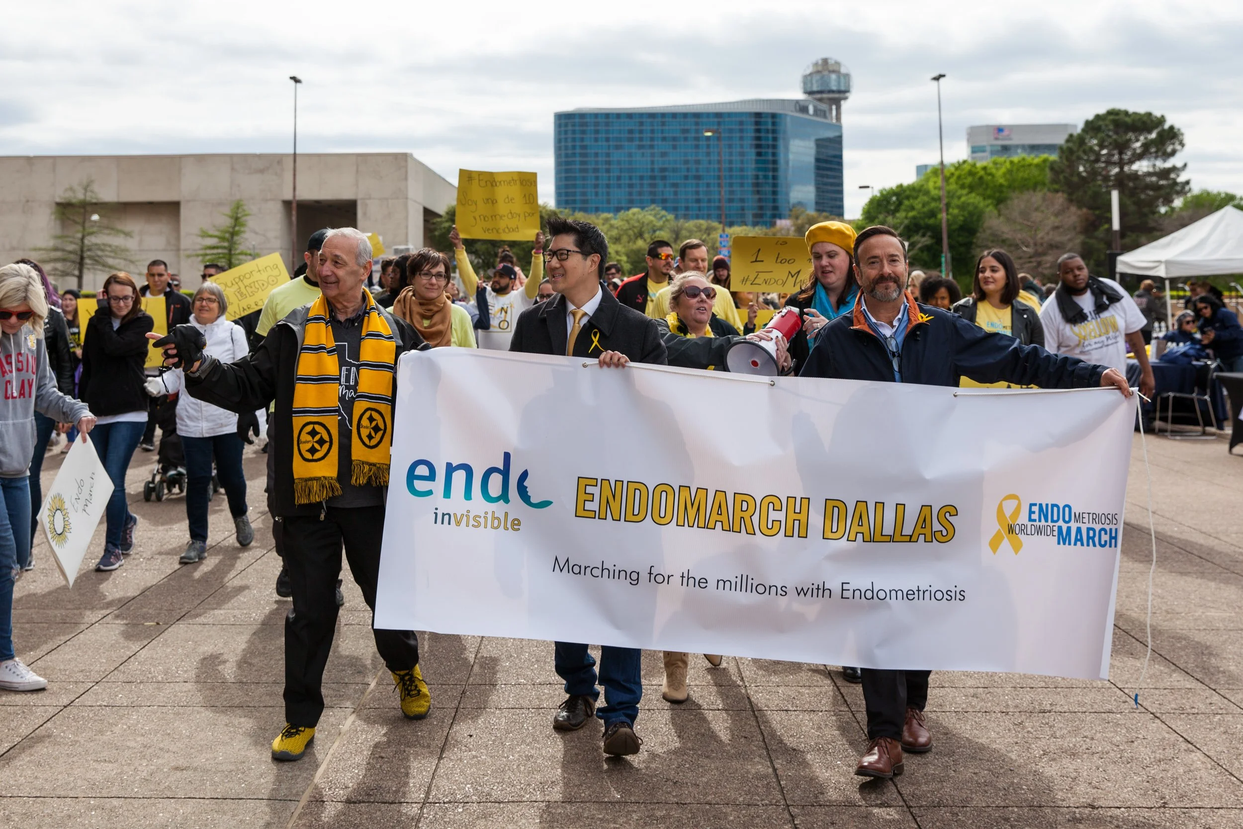Participants march behind a Worldwide EndoMarch Dallas banner during a nonprofit advocacy and awareness event.