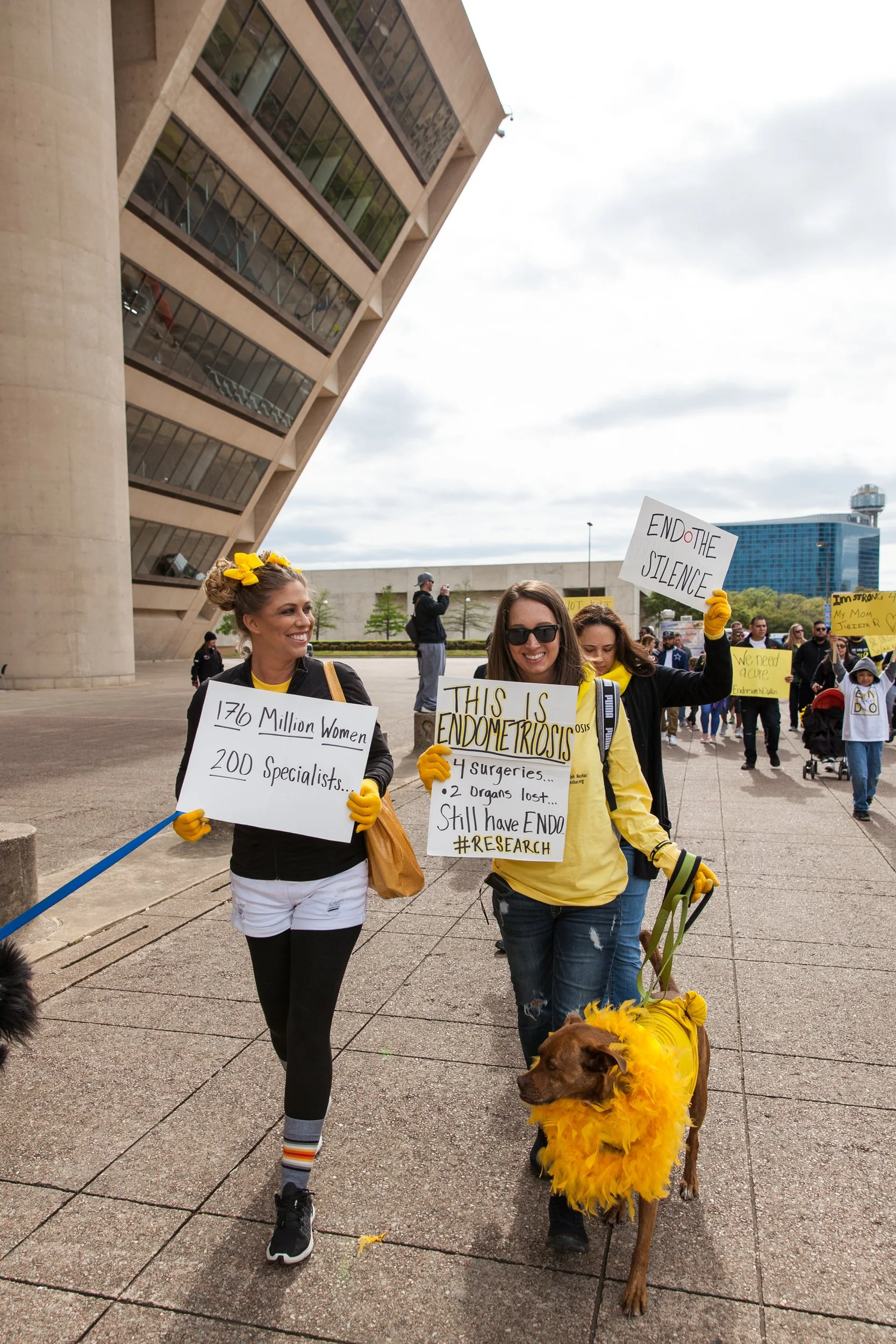 EndoMarch participants pose with handmade advocacy signs and a dog, capturing the personal stories and community behind the cause.