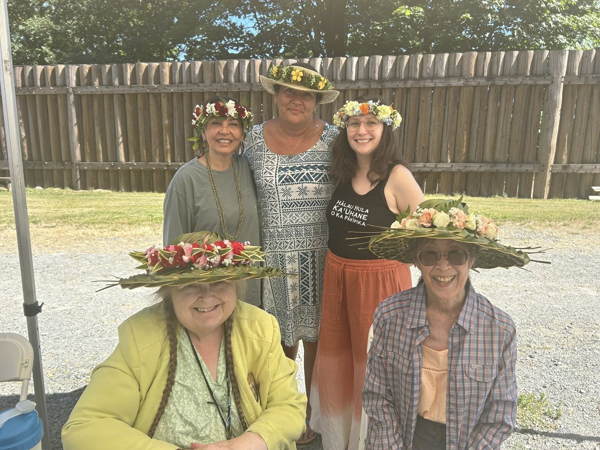 5 workshop participants, all with flower lei on their heads and 3 with papale (hats) on.