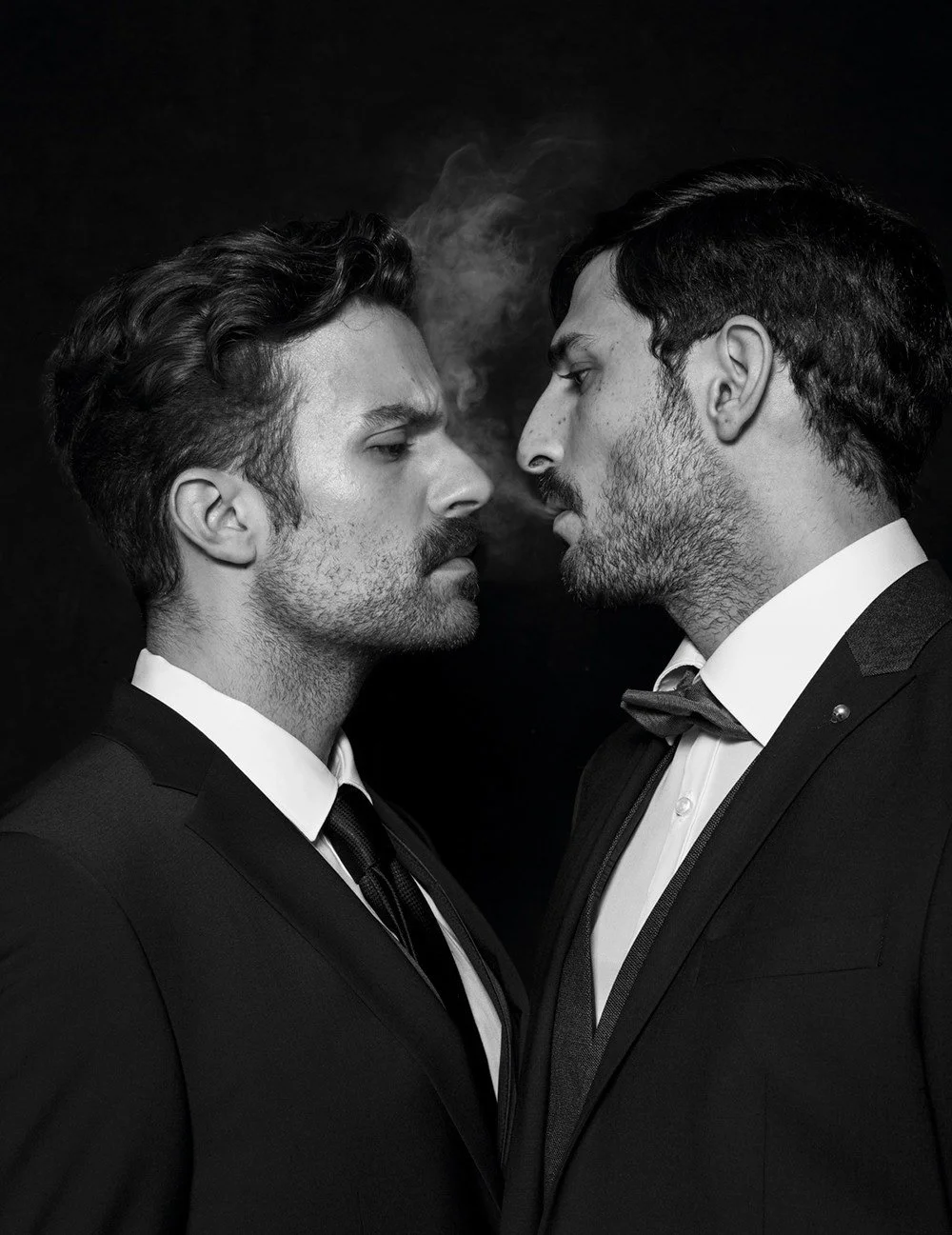 Two men in suits facing each other with smoke between them, black and white photo.
