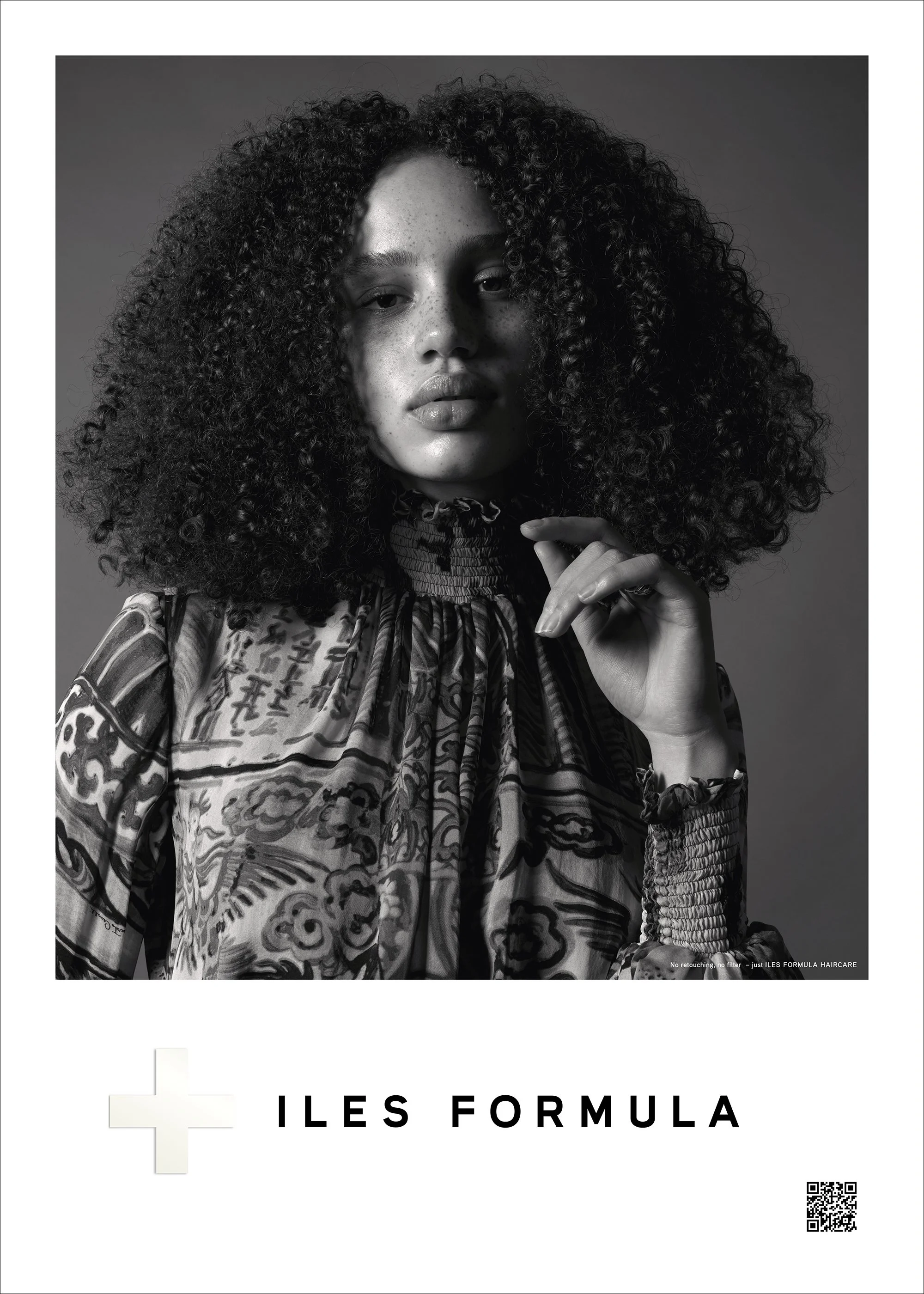 Black and white image of a person with curly hair wearing a patterned top, holding their hand near the face, featuring "ILES FORMULA" text at the bottom.