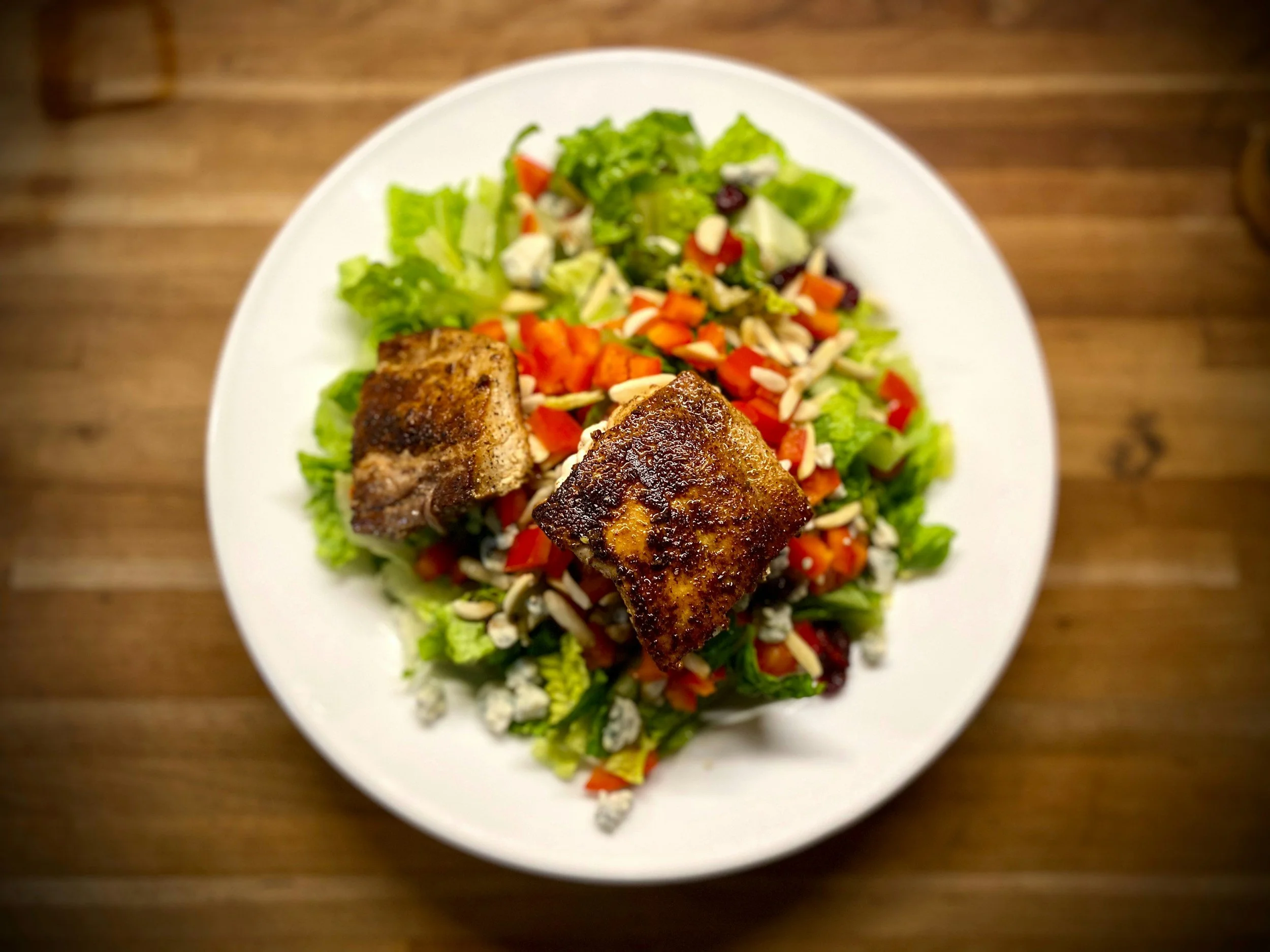 Mediterranean Salmon Salad with arugula, cherry tomatoes, feta, and lemon dressing on a white plate – healthy anti-inflammatory recipe
