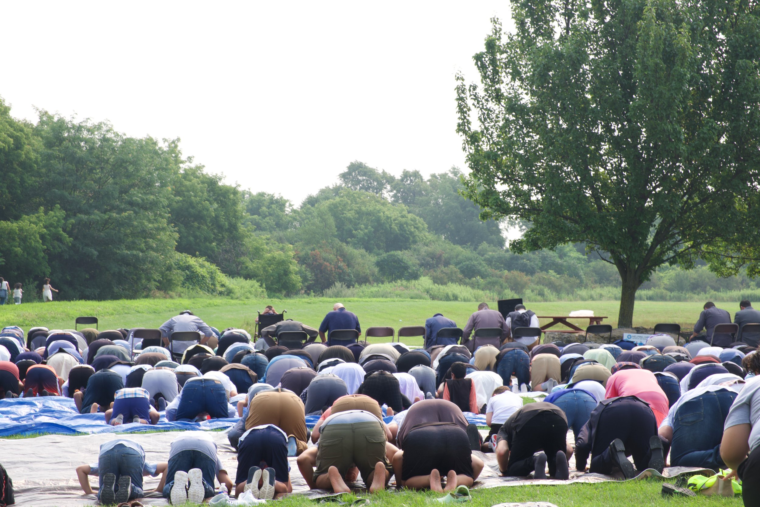 Large group bowed in prayer in open field