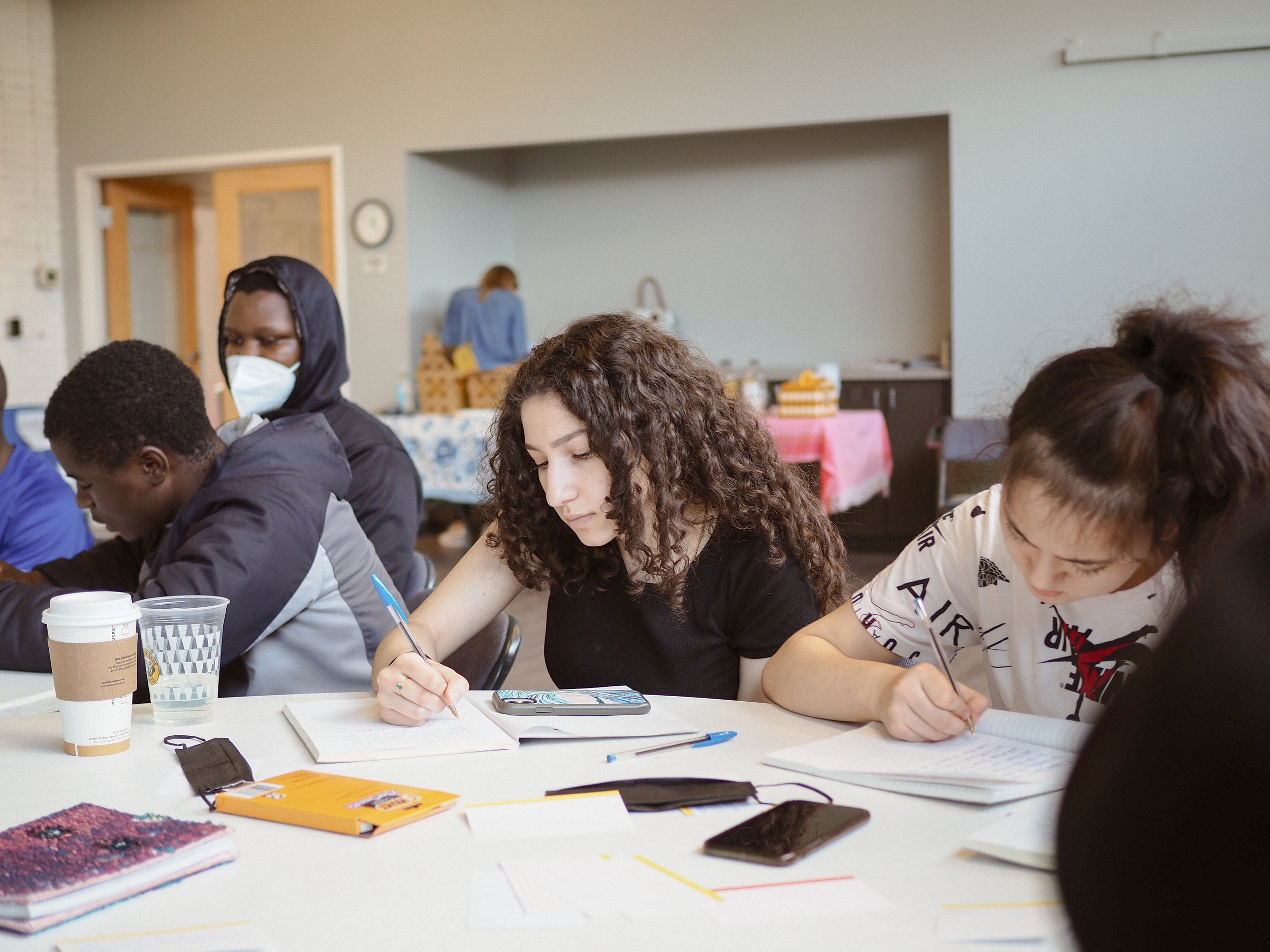 Youth writing together around tables