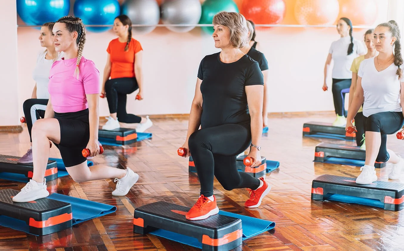Group session with women  in a step class holding dumbells