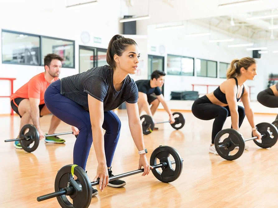 Group fitness class lifting barbells together during a Body Pump strength training session