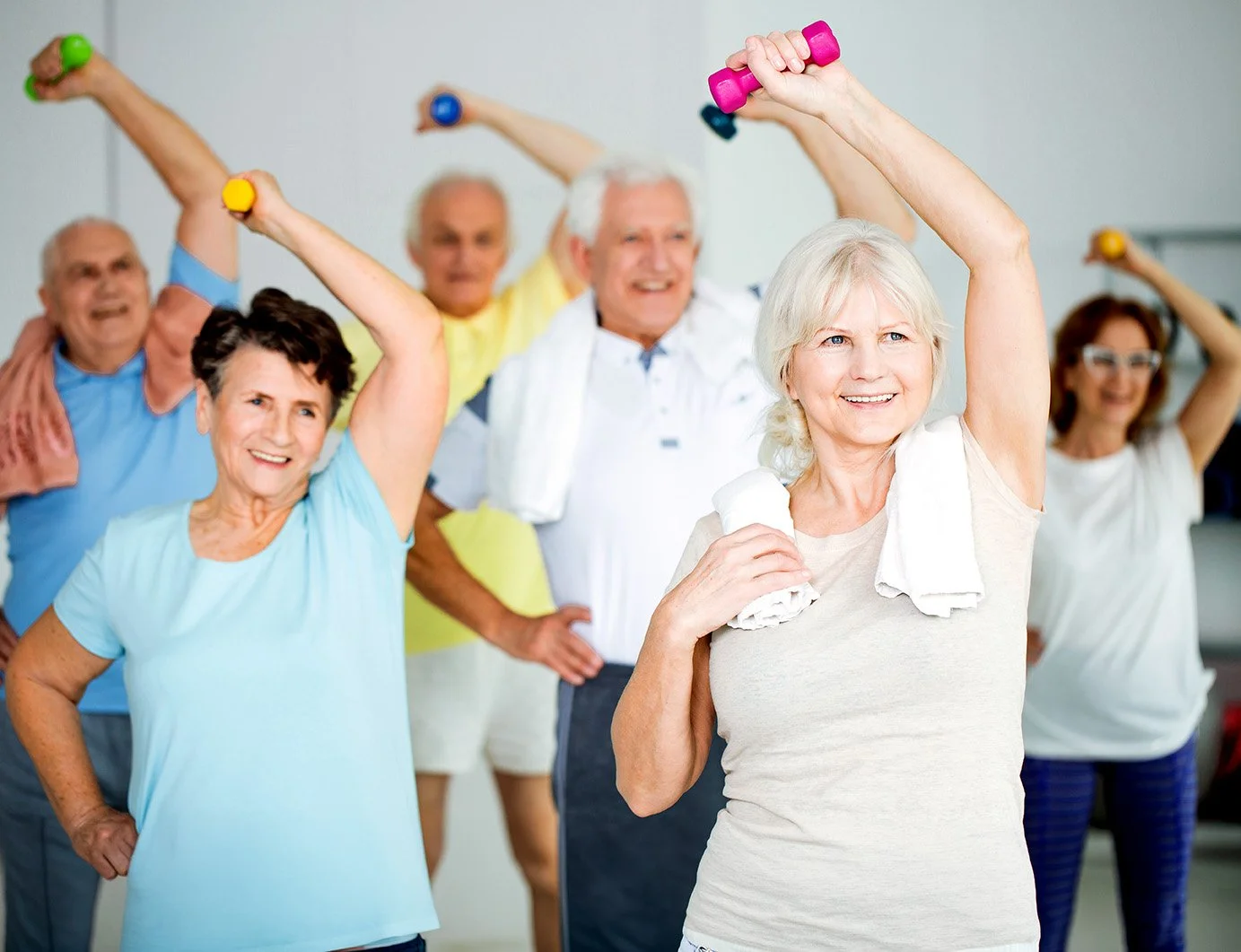Mature men and women stretching with weights in a Mature strenght buidling
