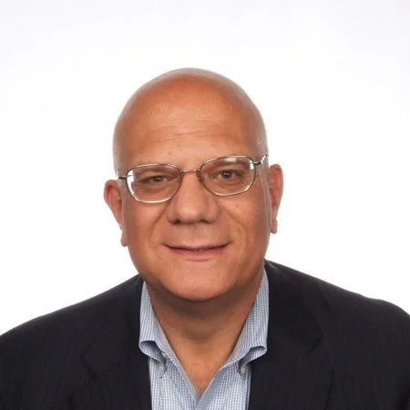 Bald man wearing glasses and a suit smiling against a white background.