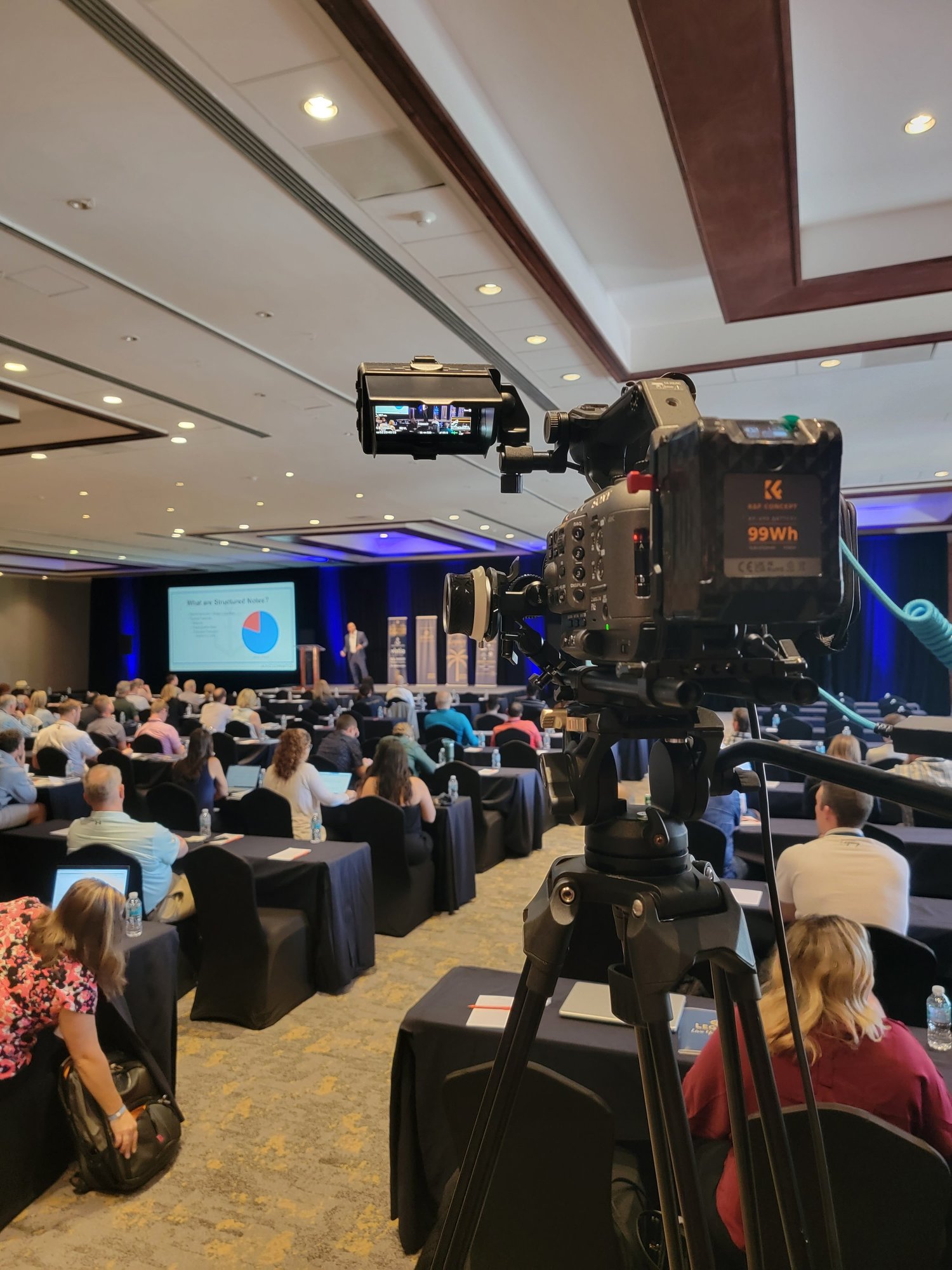 Camera filming a presentation at a corporate conference event