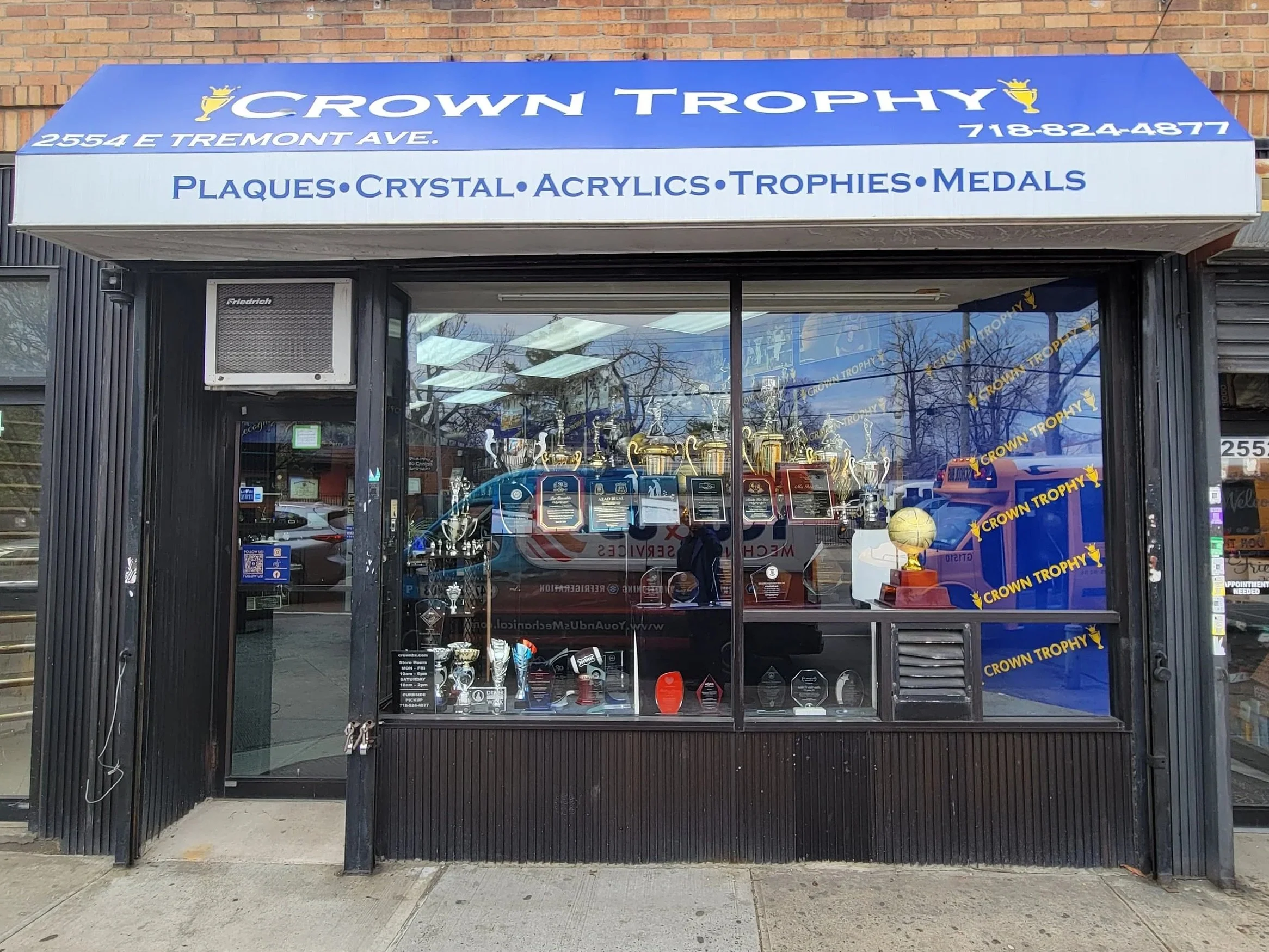 Image of Crown Trophy store front with store owner outside in the Bronx, New York