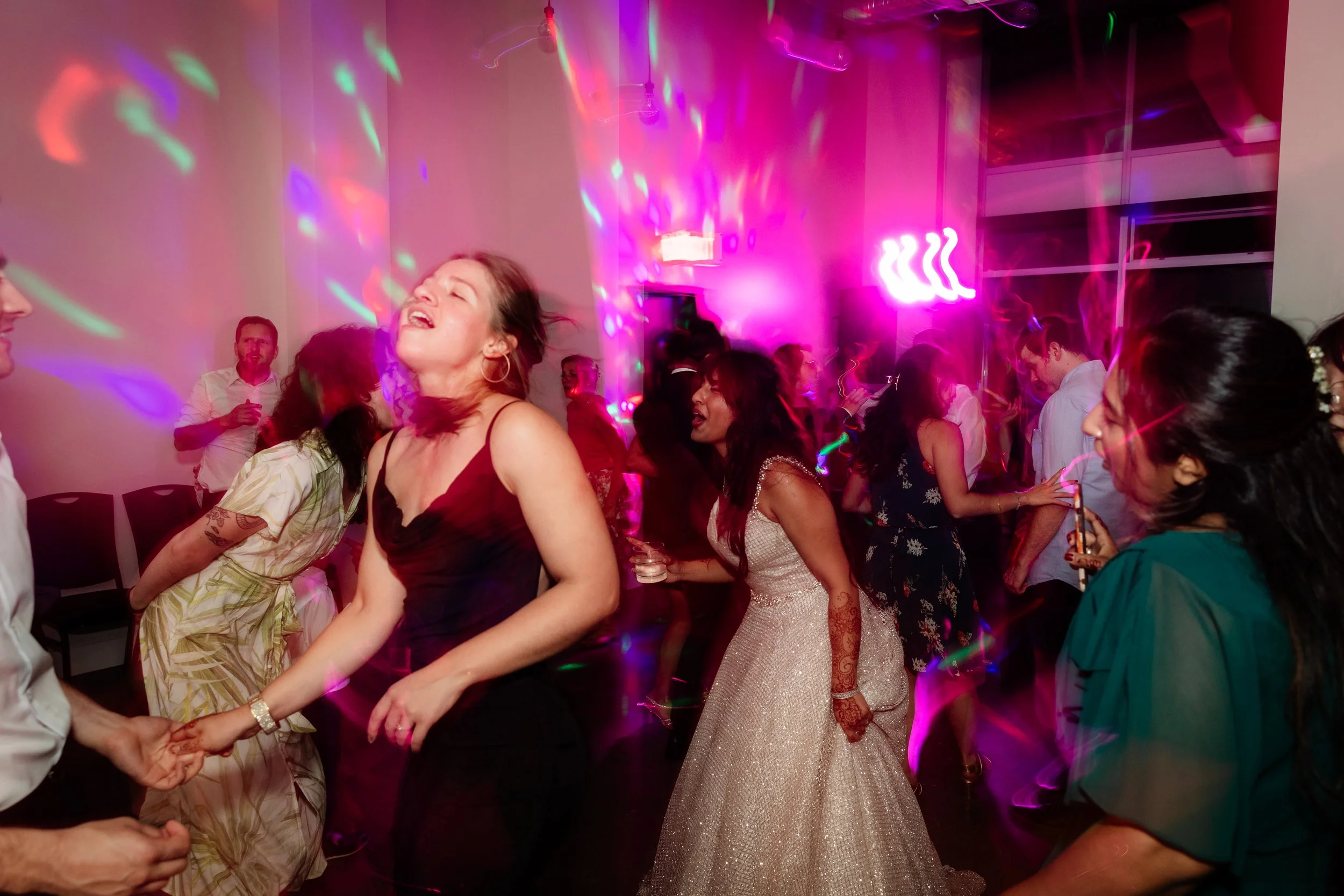 People dancing and enjoying a party with colorful lights and vibrant atmosphere.