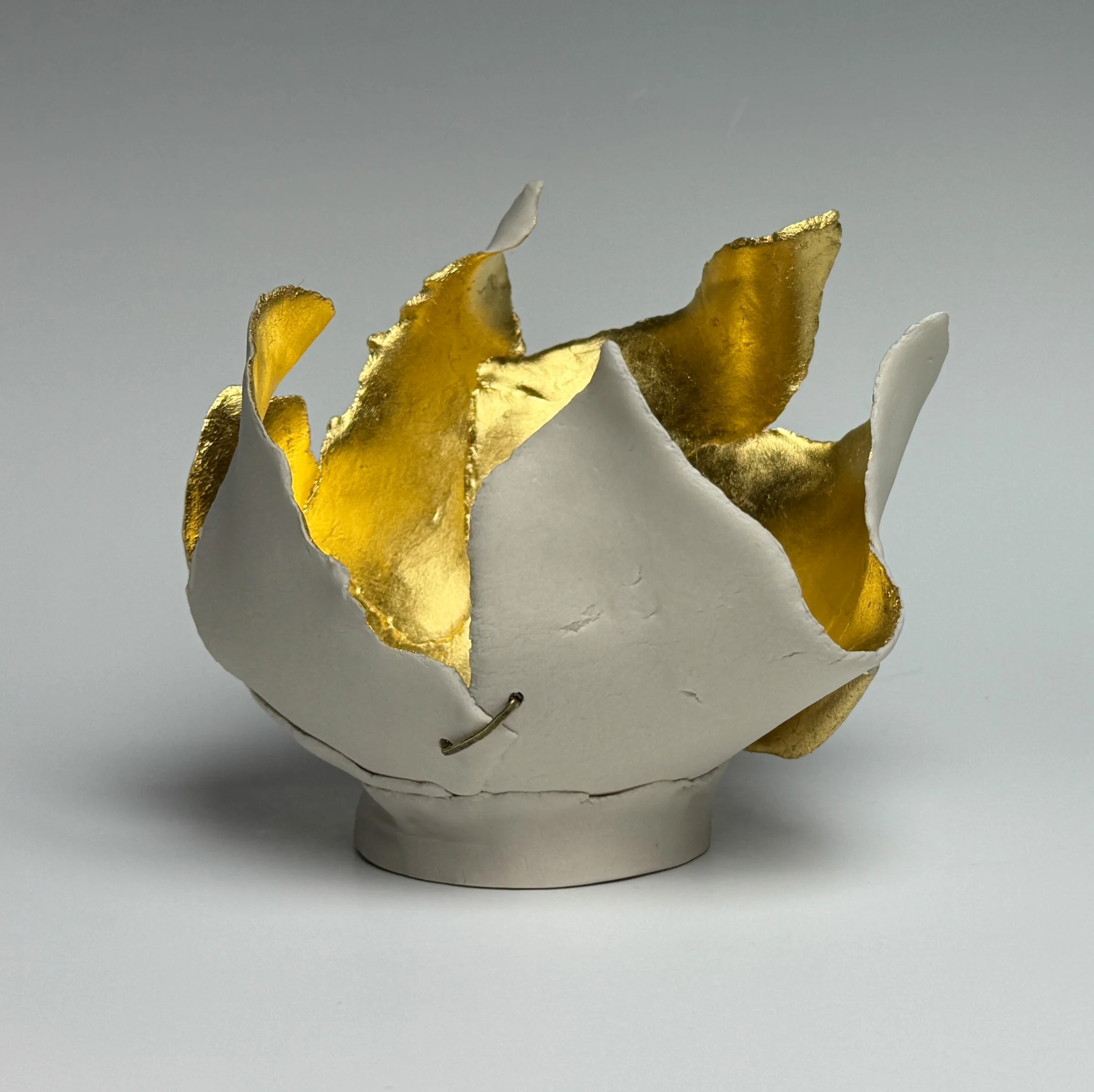 #14, Beauty Series	
5.75" H x 6" x 6"	
Porcelain, 23.75K Gold Leaf, Hammered Brass Wire Staple, Cone 6, Oxidation