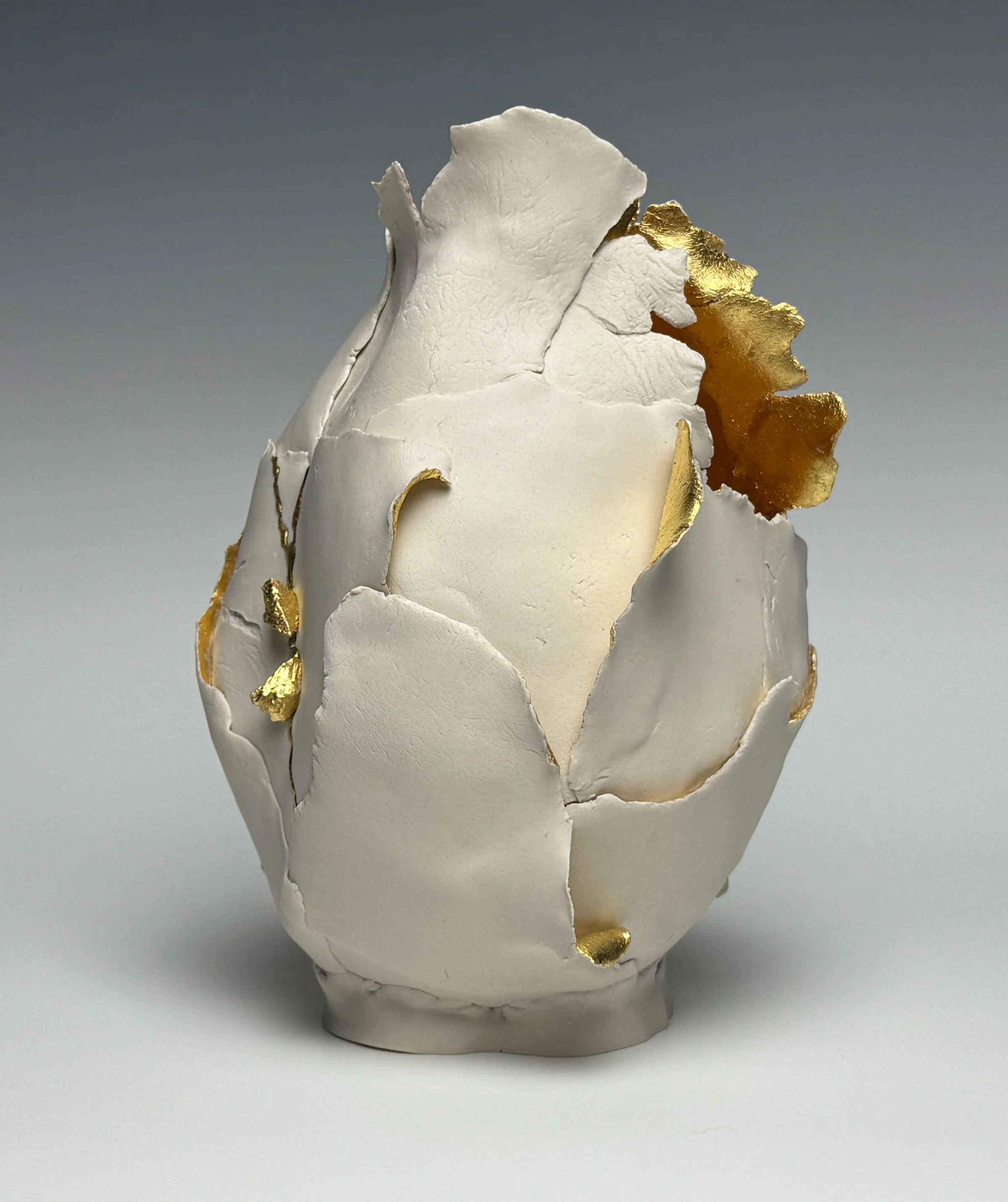 Held
8.5" H x 6" x 6"
Porcelain, 23.75K Gold Leaf, Hammered Brass Wire Staple, Porcelain "Stones", 
Cone 6, Oxidation