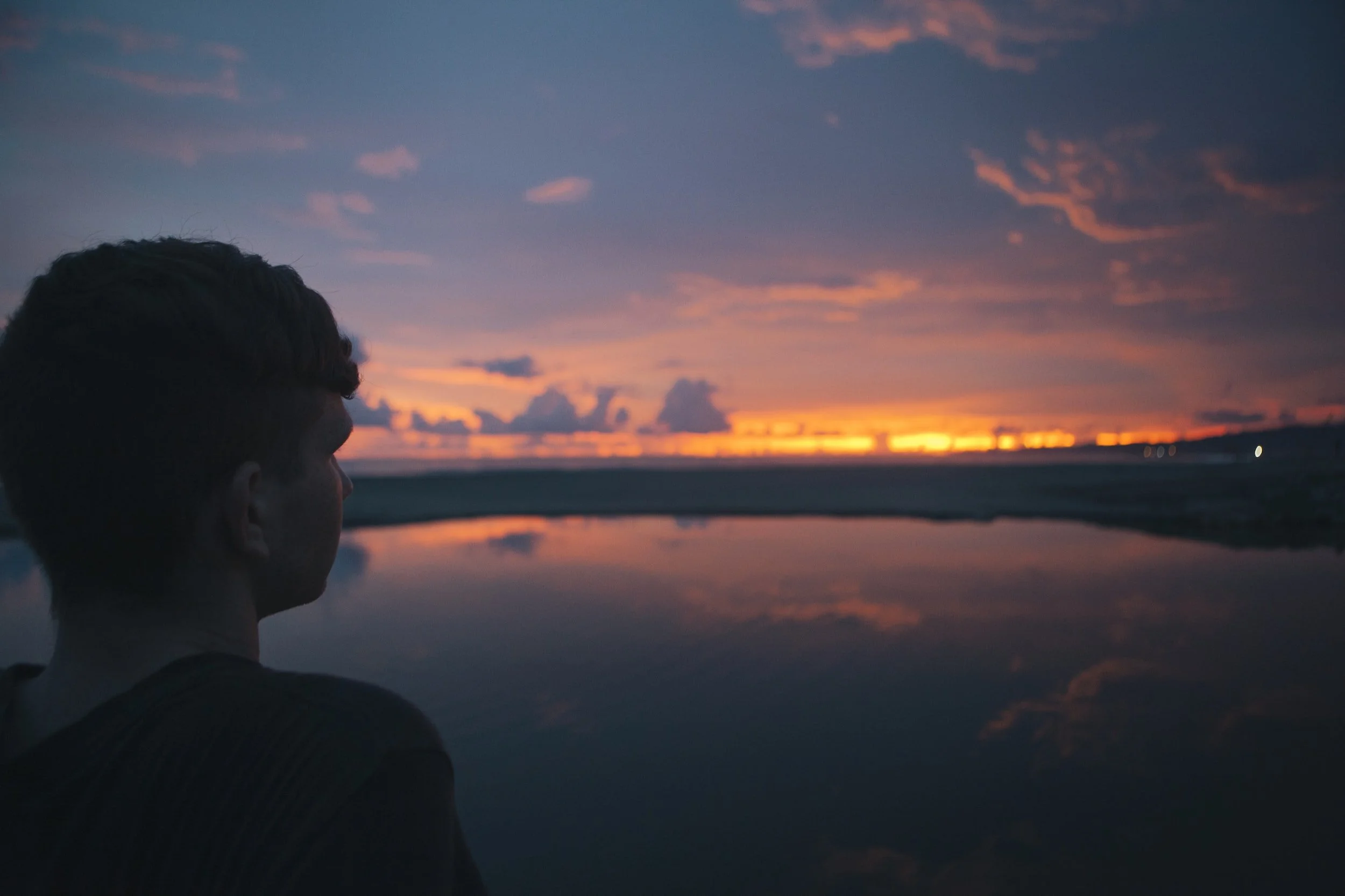 Someone looking over a lake at the sunset
