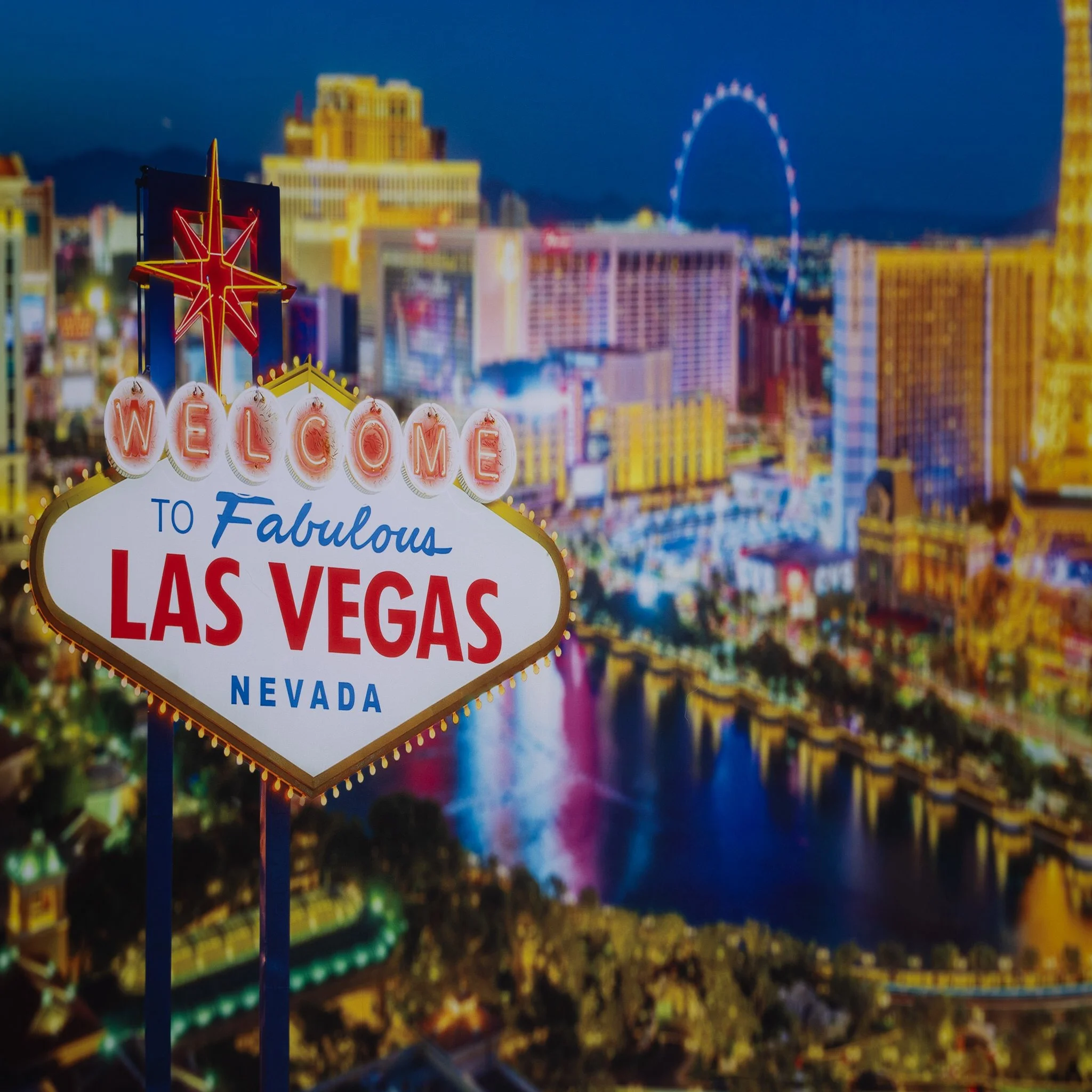 Night view of Las Vegas skyline with illuminated signs and a clear welcome sign in the foreground.