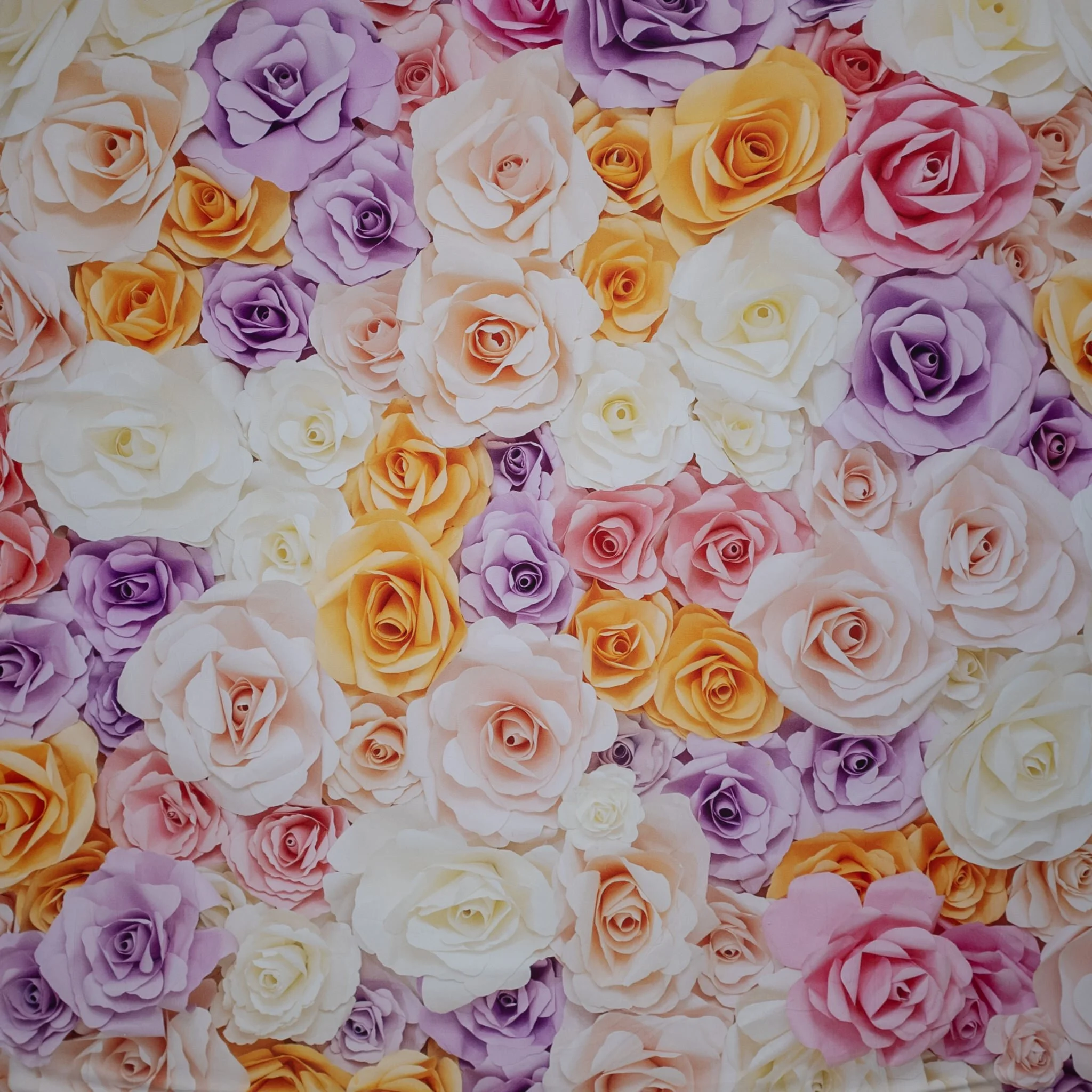 A colorful arrangement of paper roses in shades of white, pink, purple, yellow, and orange.