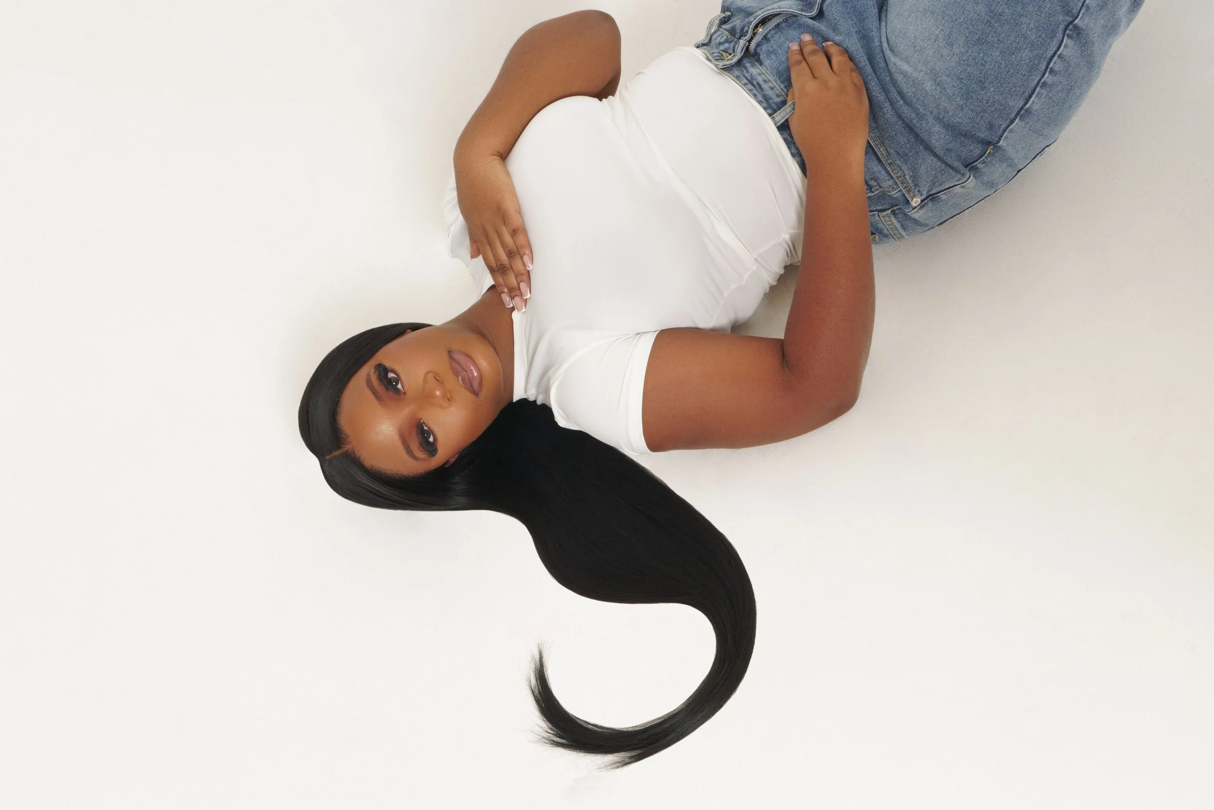 Model lying down with long hair wearing a white T-shirt and blue jeans
