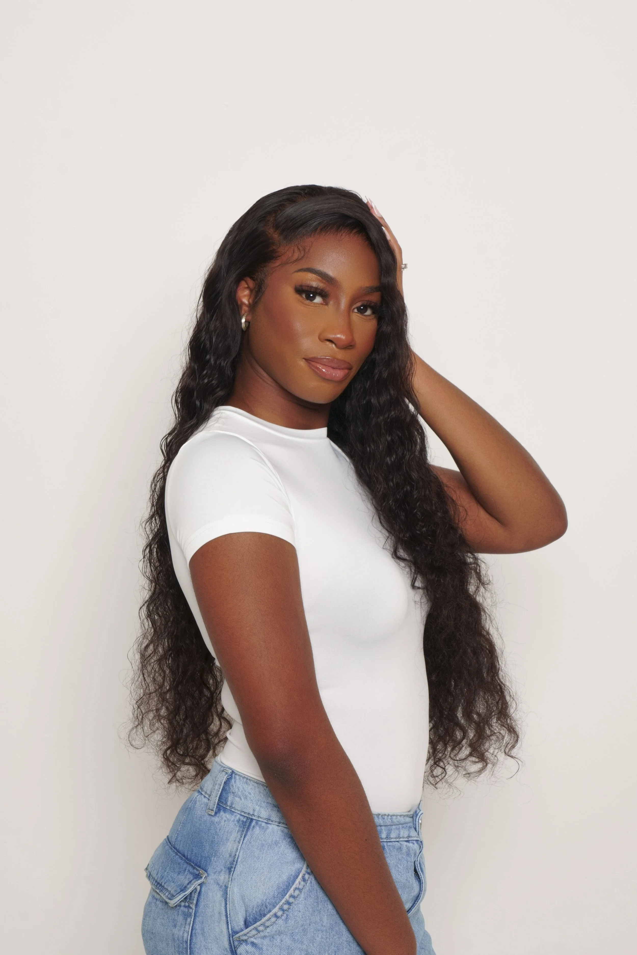 Model with curly hair wearing a white t-shirt and blue jeans
