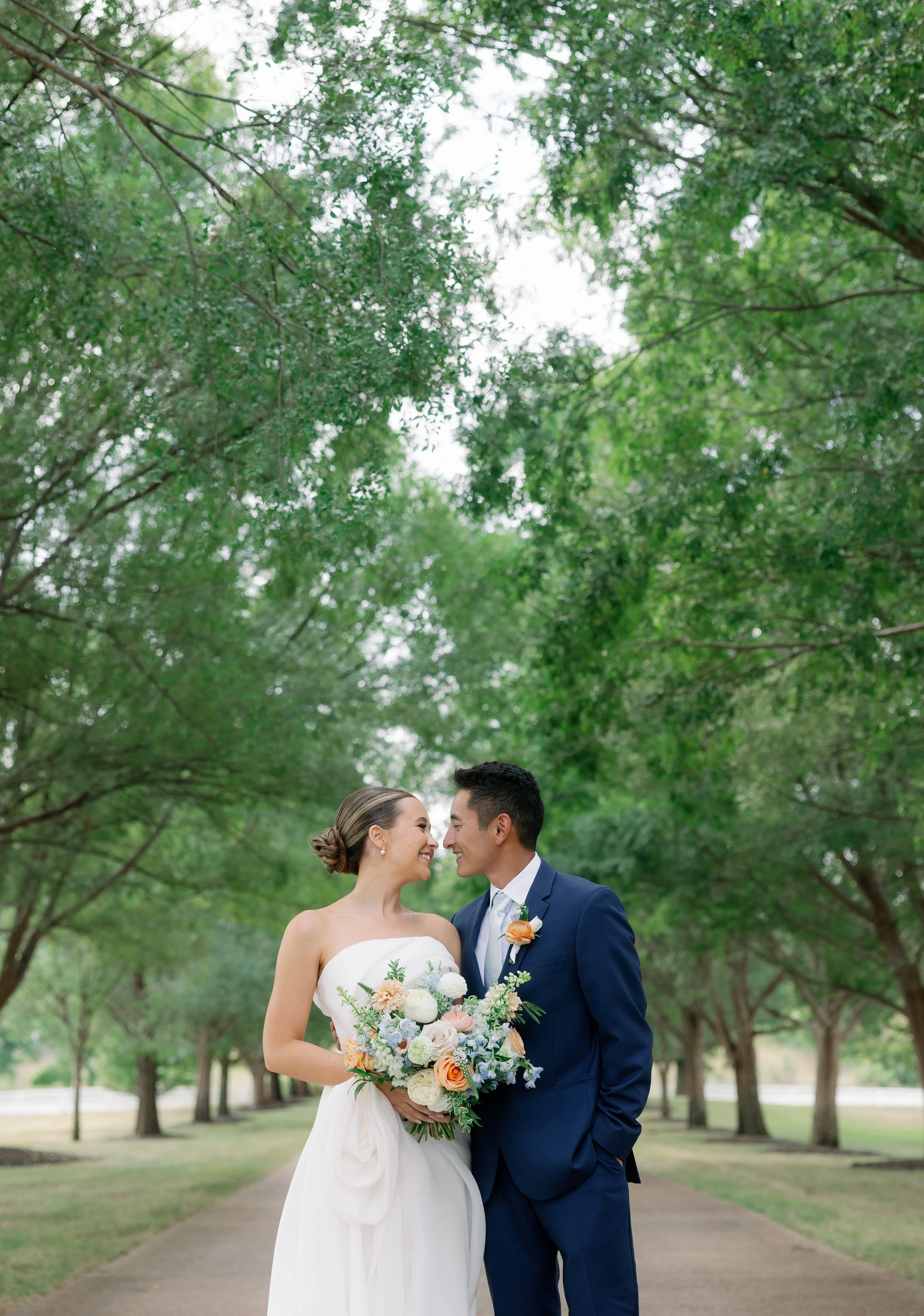 Romantic newlywed portrait with pastel blooms and bright summer lighting captured outdoors in Fulton, Missouri.