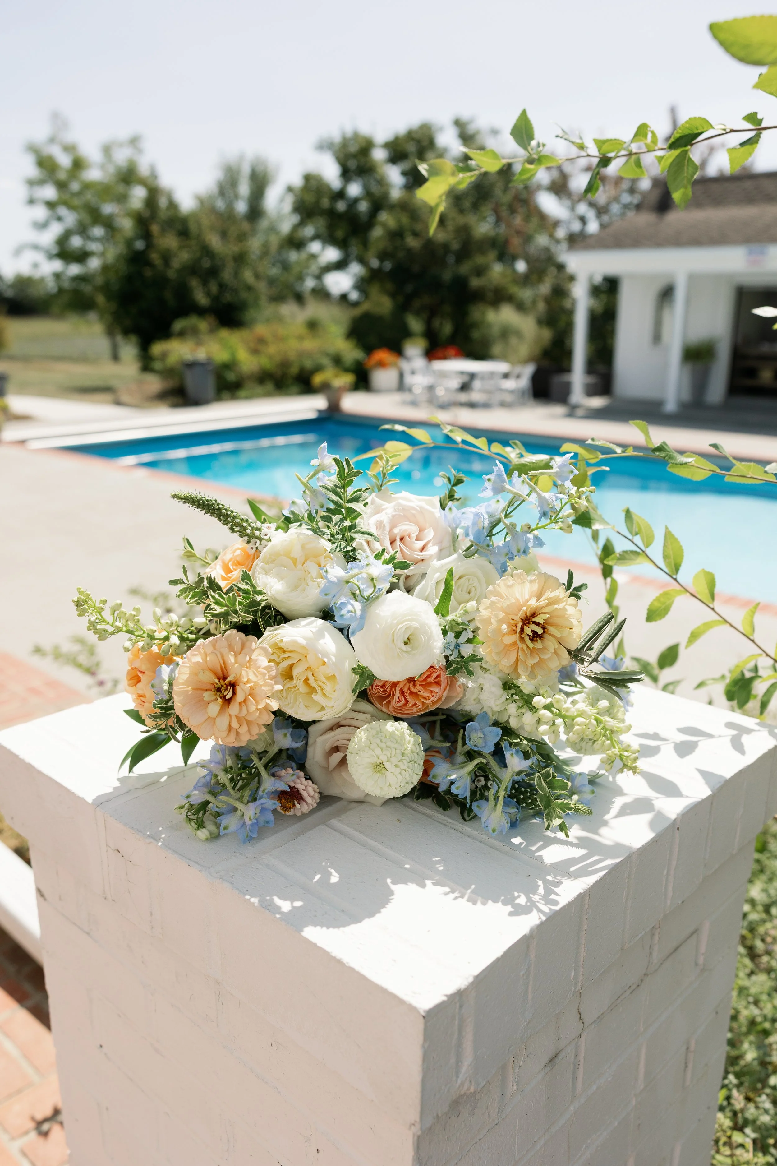 Set on pale stone, the pastel blue and peach bouquet feels bright and airy. This clean background highlights floral details and works perfectly for “elegant summer bouquet inspiration.”