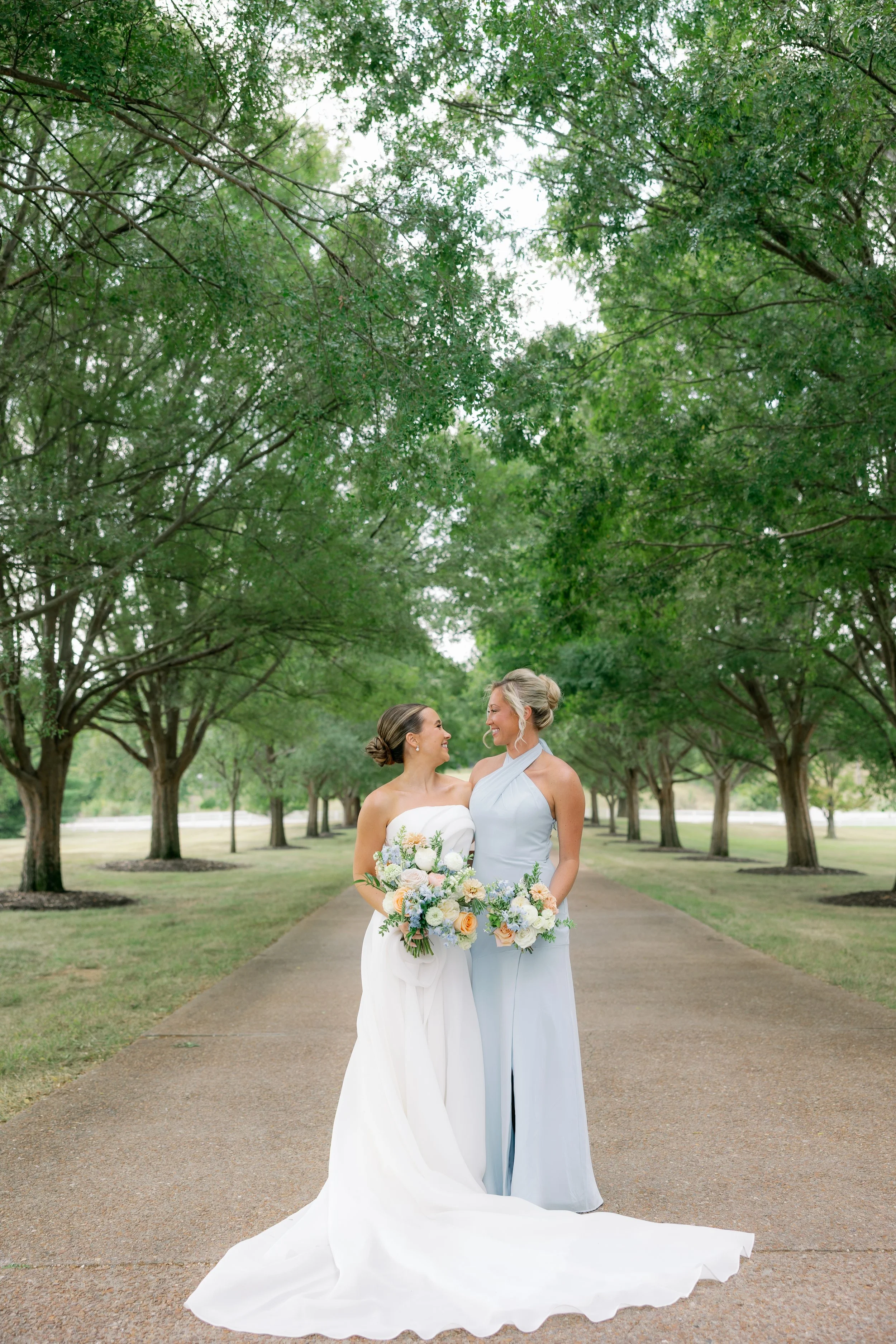 Bridesmaids in pastel blue dresses holding garden-inspired bouquets designed to enhance Callie’s soft wedding palette.