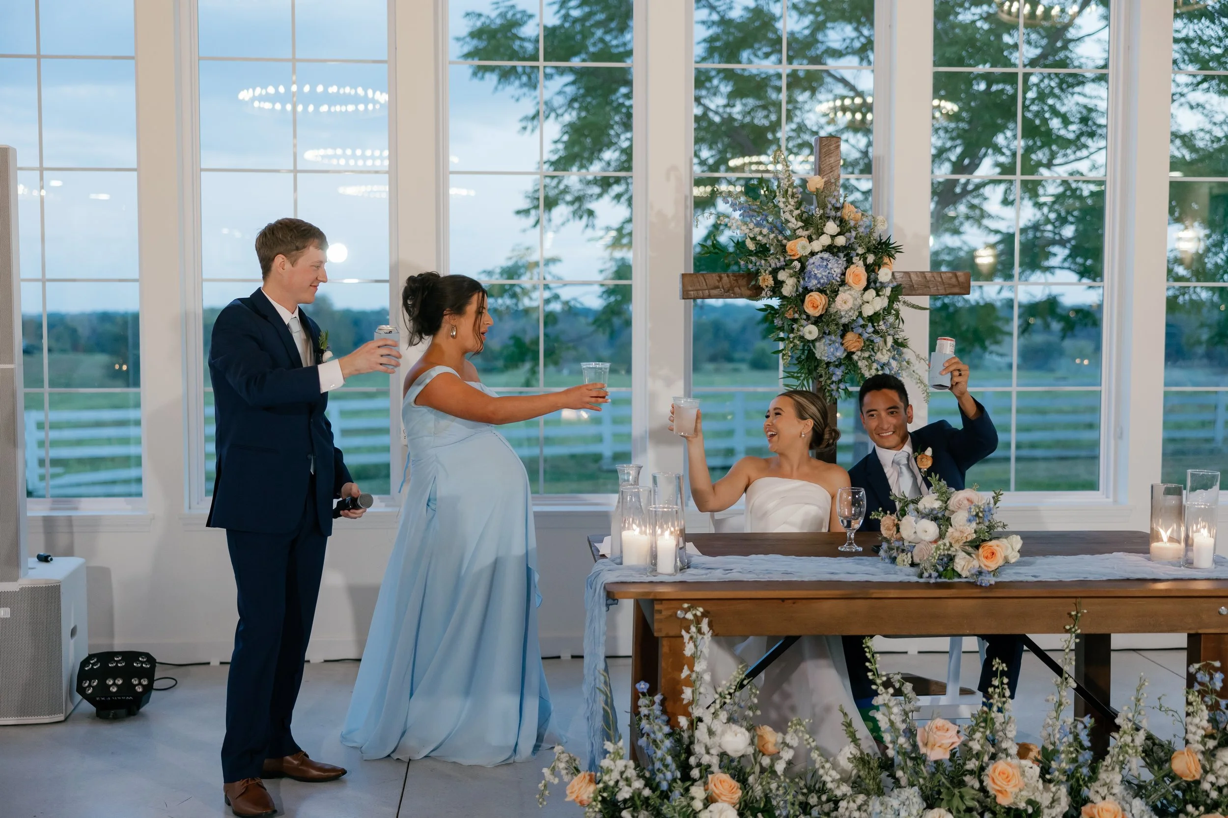 A celebratory toast takes center stage as pastel blue and peach florals wrap the head table. The airy floral design adds charm and elegance to the indoor reception at The Callaway Jewel.