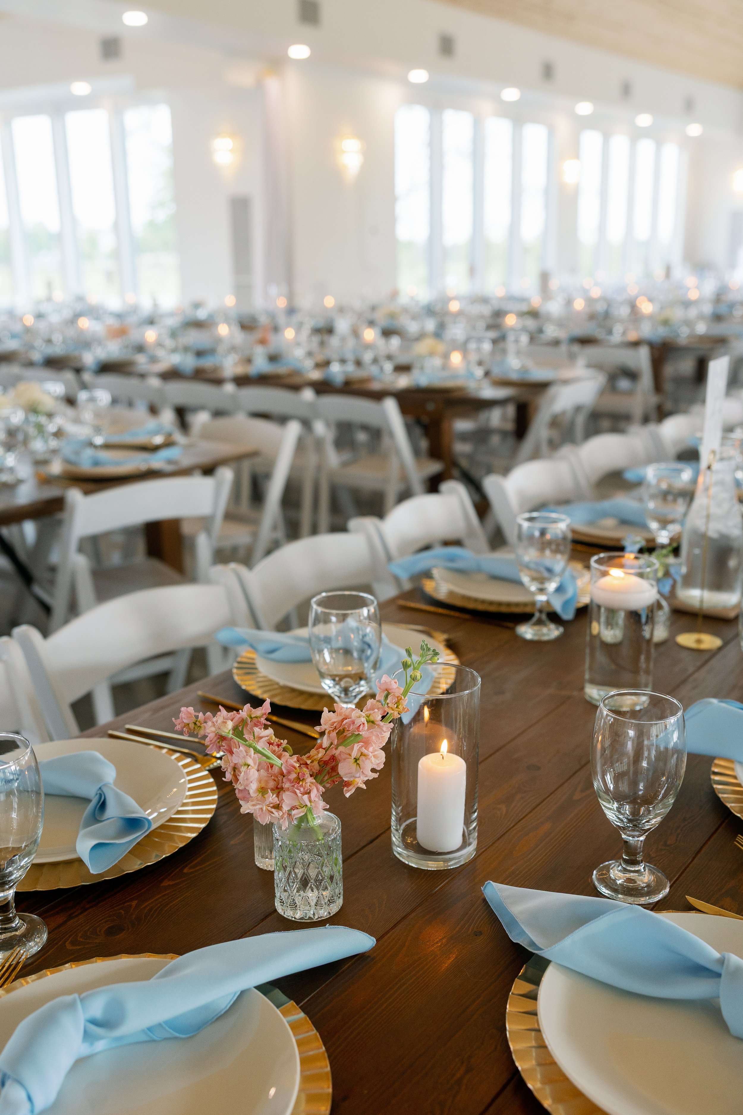 Classic white and peach centerpieces with pastel blue accents for a timeless indoor wedding reception.