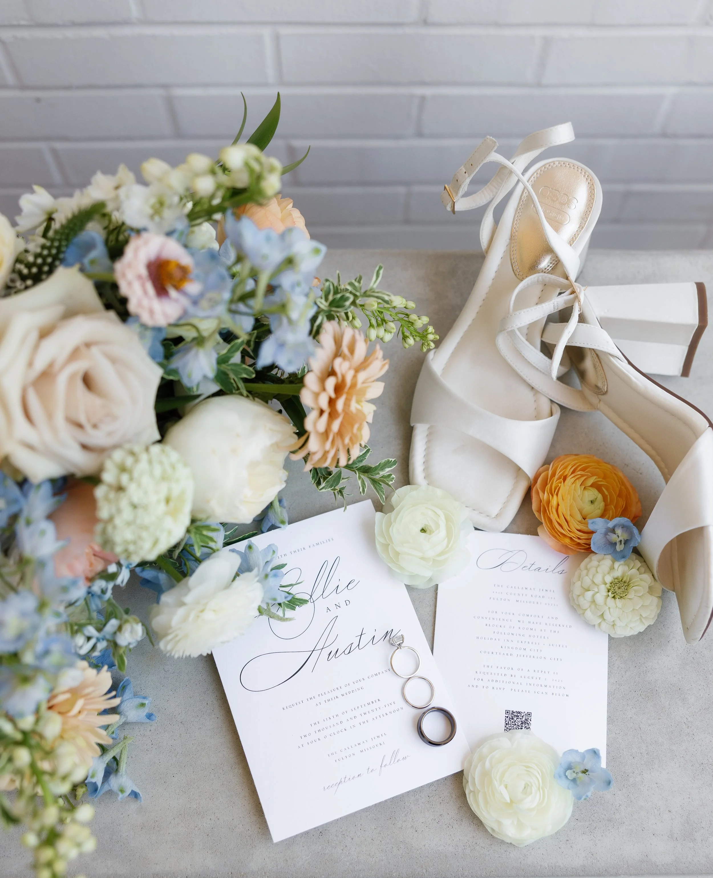 Flatlay of wedding details featuring pastel blue stationery, white florals, and peach accents for Callie & Austin’s Missouri wedding.